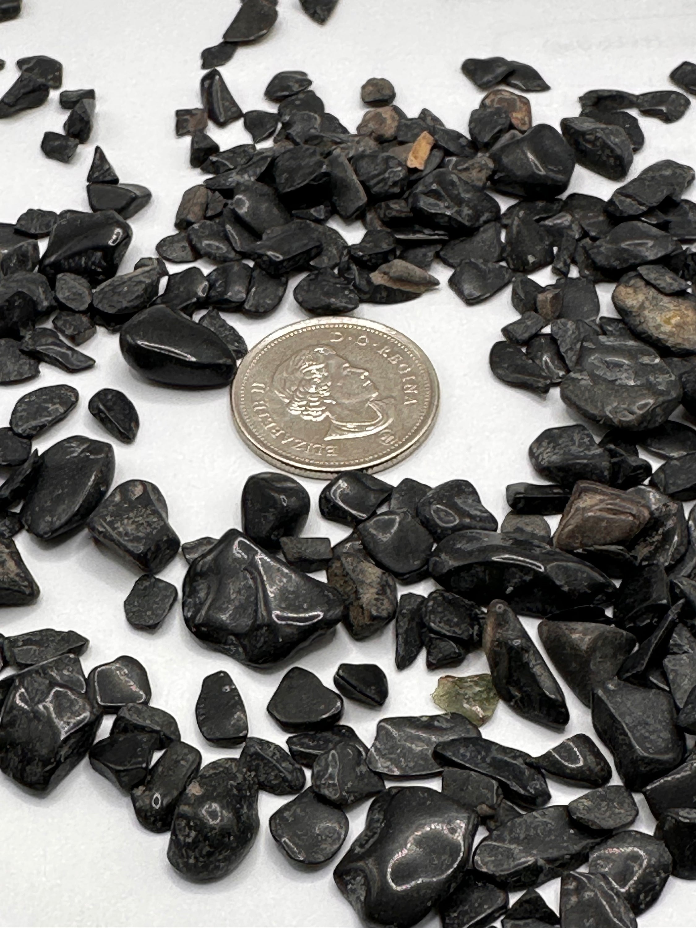 A collection of rough cut black tourmaline chips showcasing unique shapes, sizes, and Mica and Quartz inclusions.