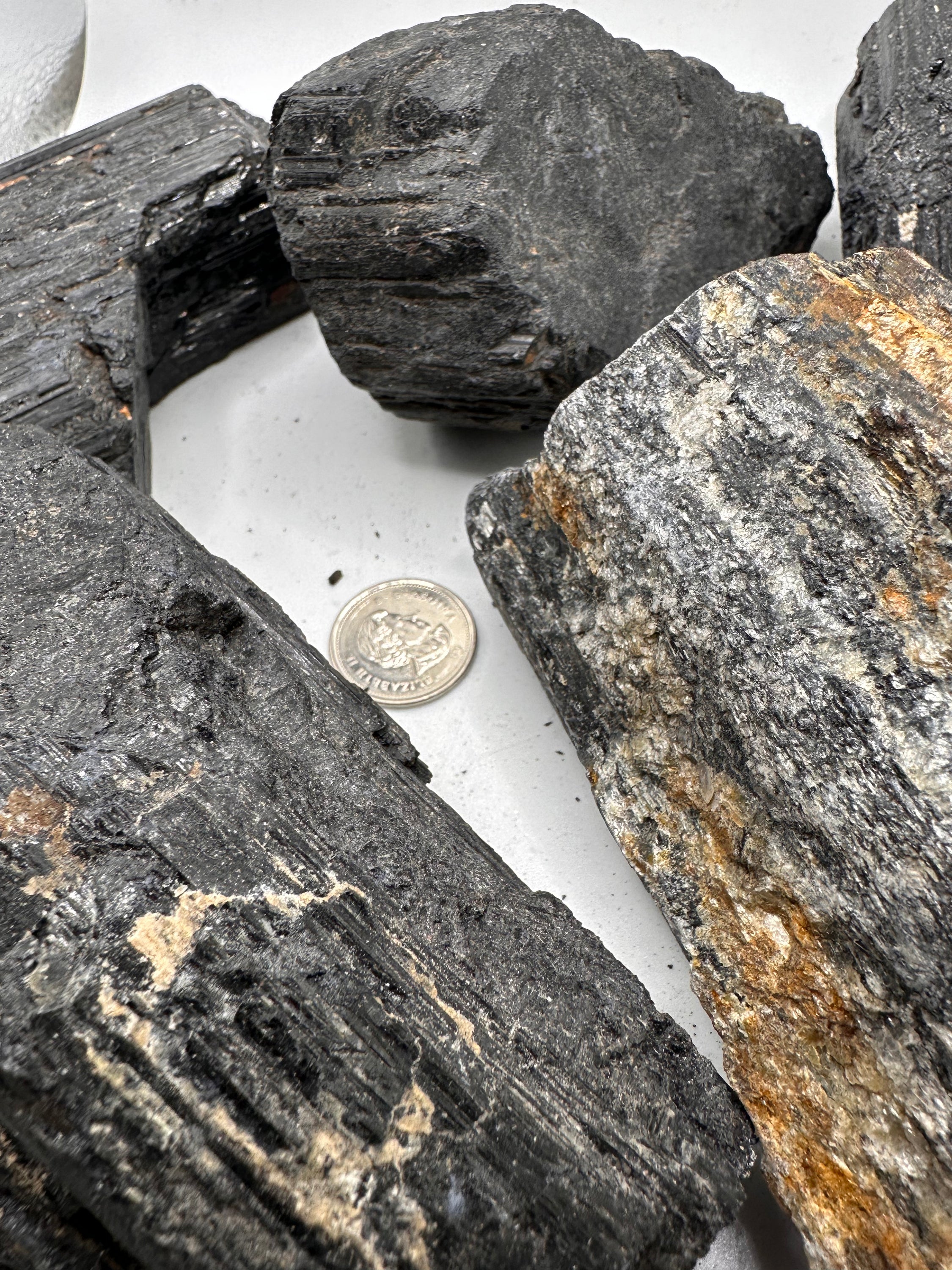 A collection of unique rough cut Black Tourmaline stones, showcasing their natural beauty with Mica and Quartz inclusions.