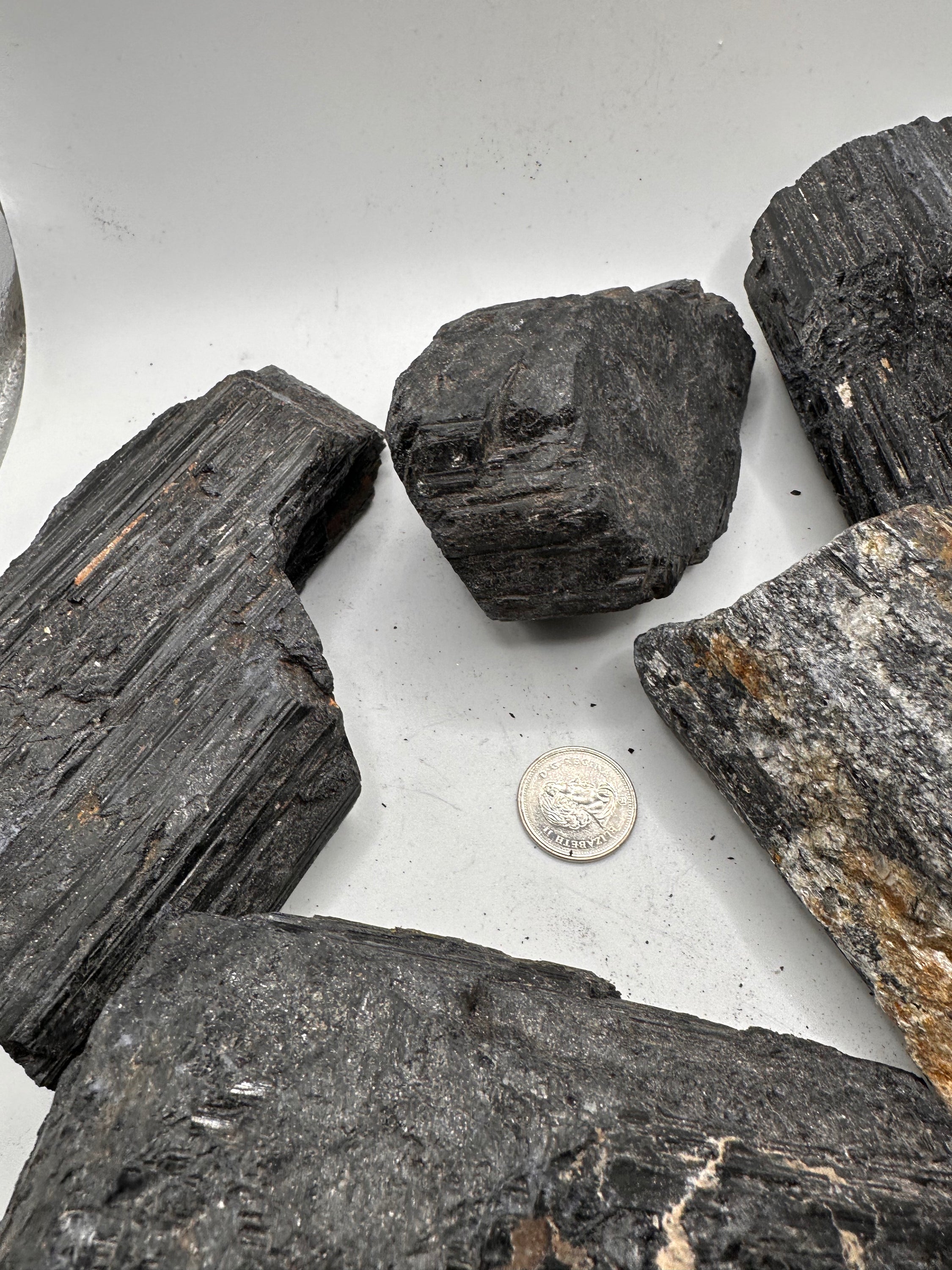 A collection of unique rough cut Black Tourmaline stones, showcasing their natural beauty with Mica and Quartz inclusions.