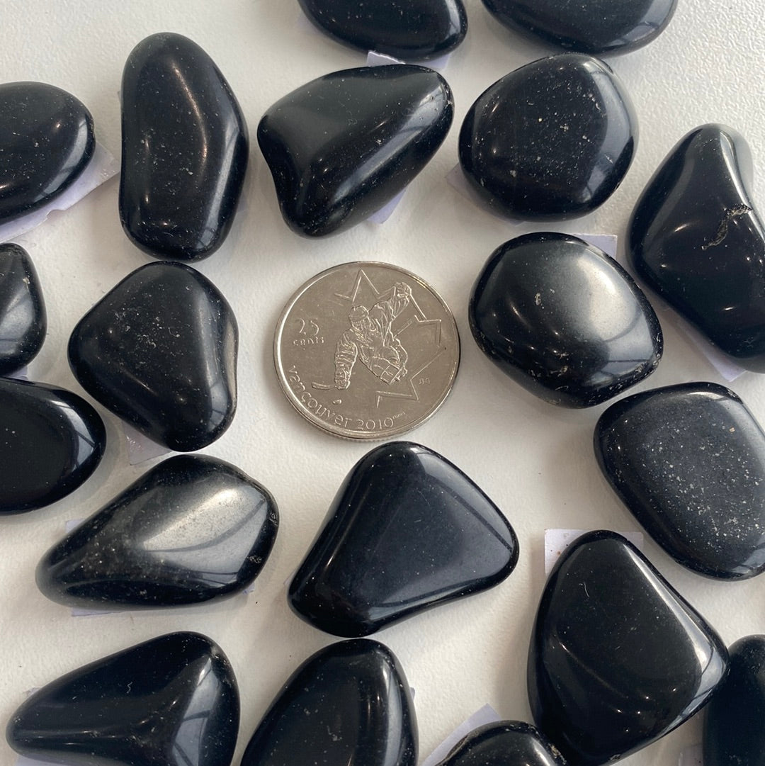 A polished Black Tourmaline Tumbled Stone showcasing its deep black color and smooth surface, ideal for protection against negativity.