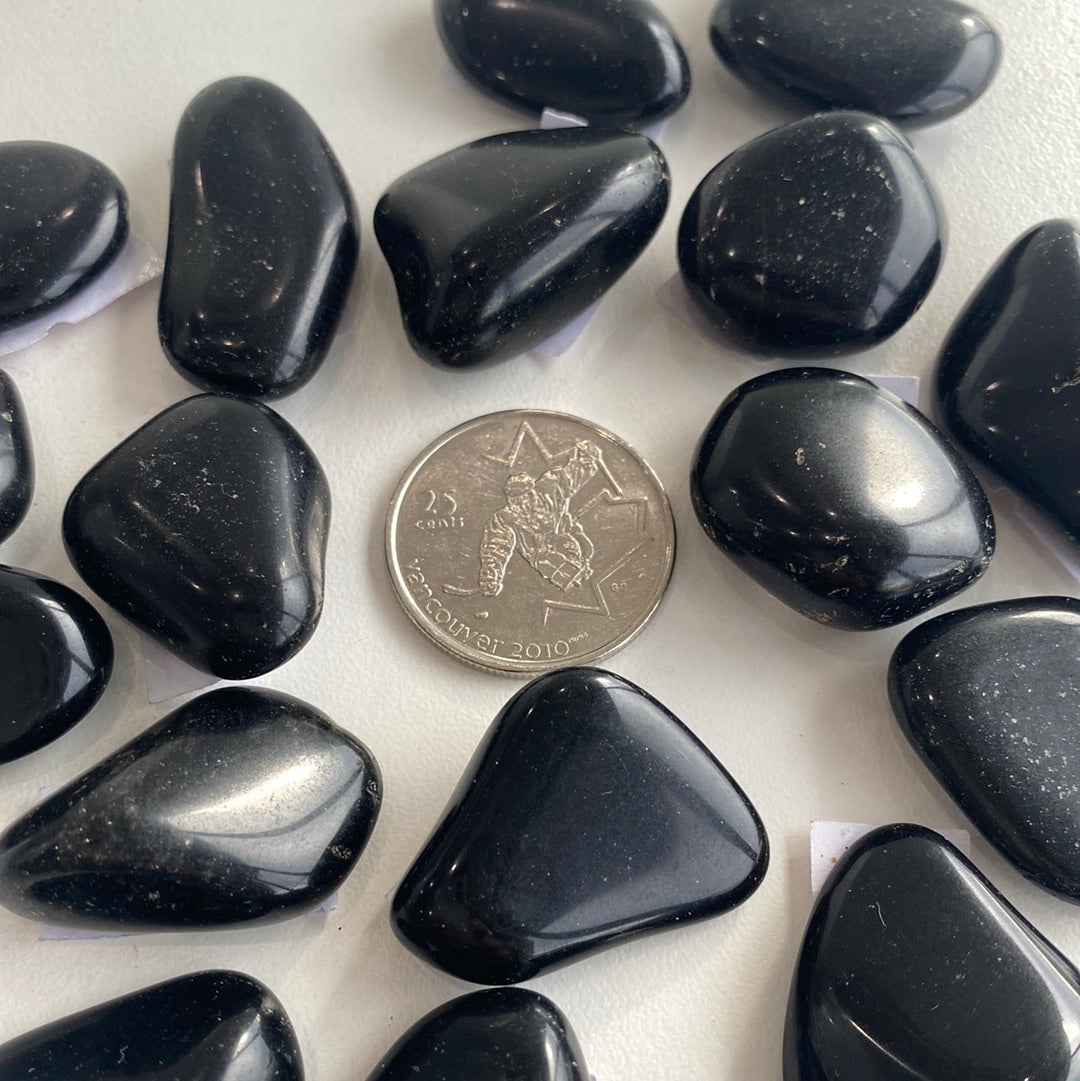 A polished Black Tourmaline Tumbled Stone showcasing its deep black color and smooth surface, ideal for protection against negativity.