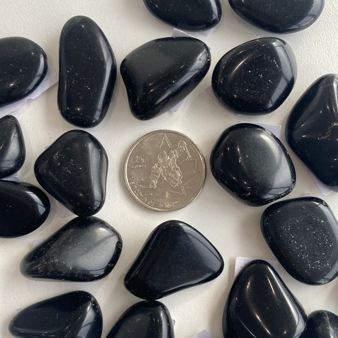 A polished Black Tourmaline Tumbled Stone showcasing its deep black color and smooth surface, ideal for protection against negativity.