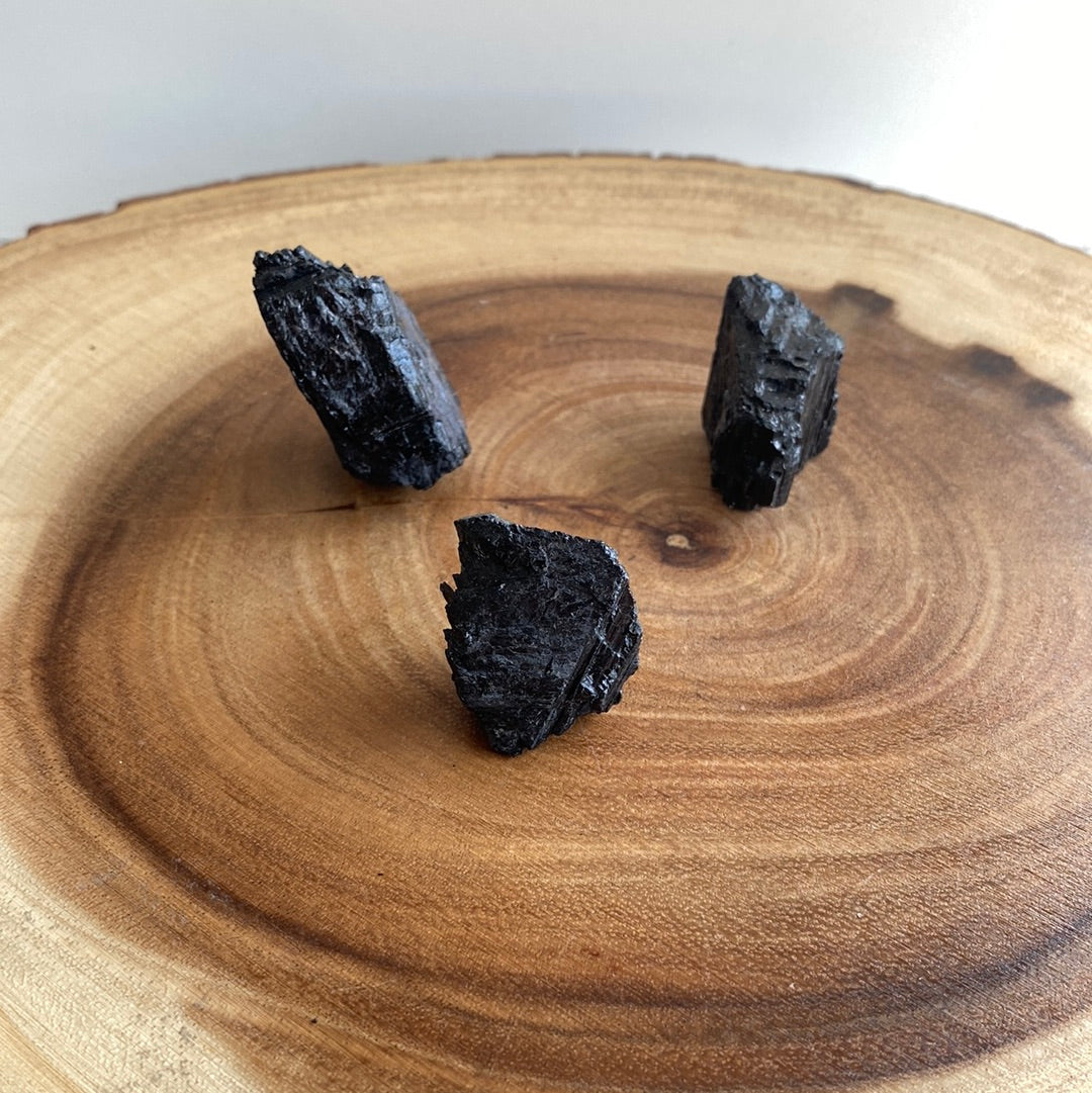 A small piece of Black Tourmaline crystal, showcasing its deep black color and natural texture, symbolizing protection and positive energy.