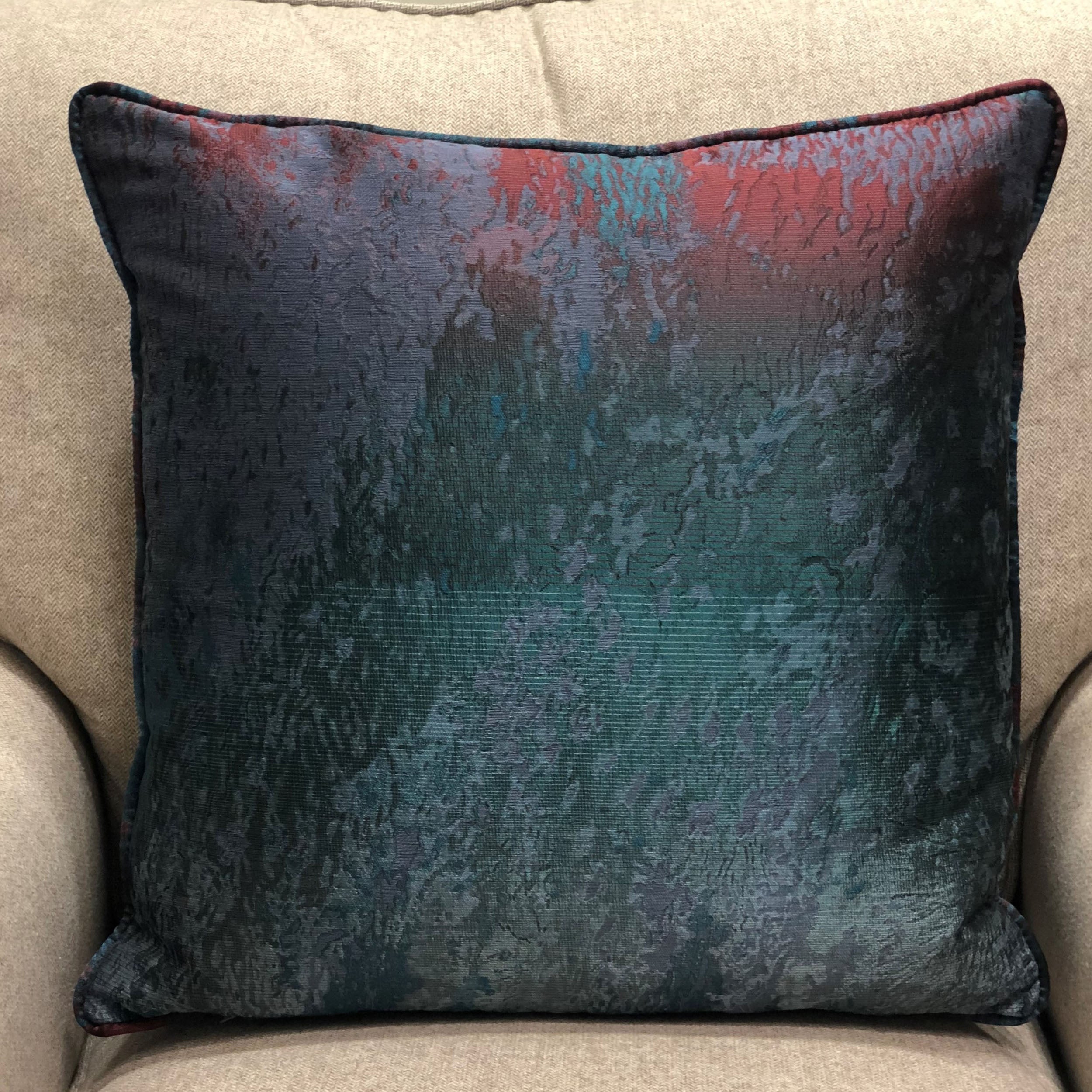 Luxurious throw pillow in blue, green, and red colors, featuring a soft velour fabric and elegant piping edge.