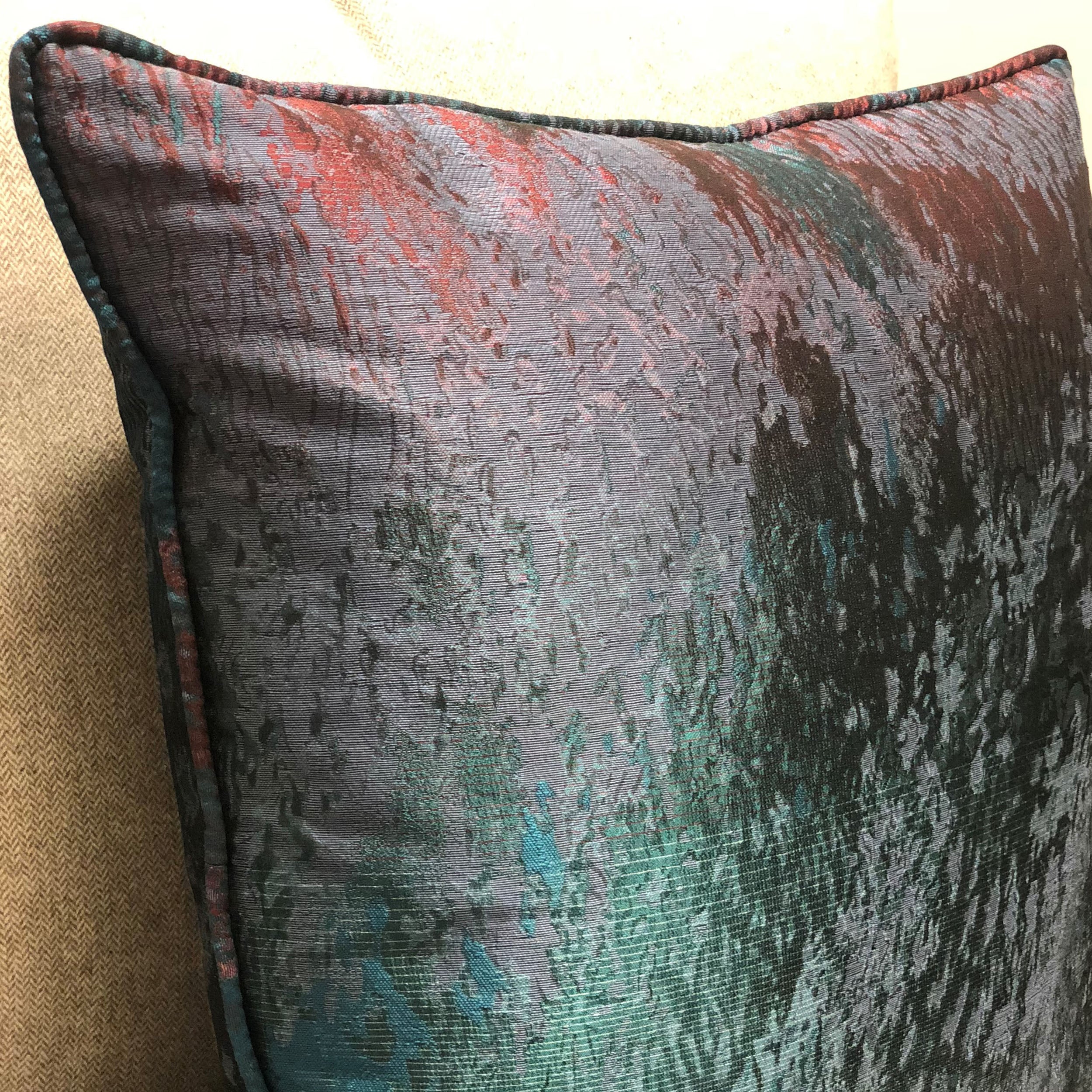 Luxurious throw pillow in blue, green, and red colors, featuring a soft velour fabric and elegant piping edge.