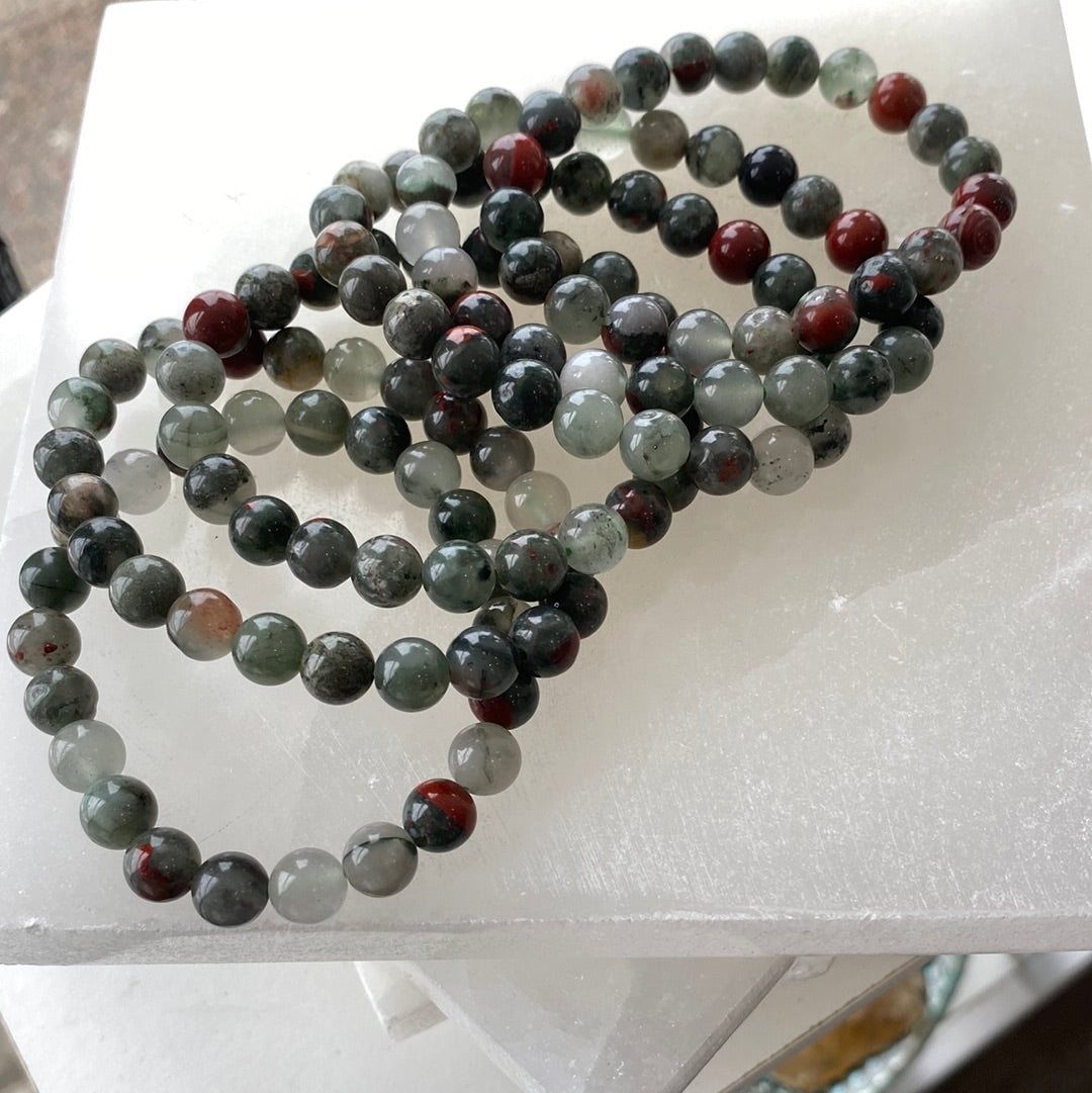 A beautifully crafted 8mm Bloodstone bracelet featuring dark green beads with red inclusions, showcasing its polished finish.