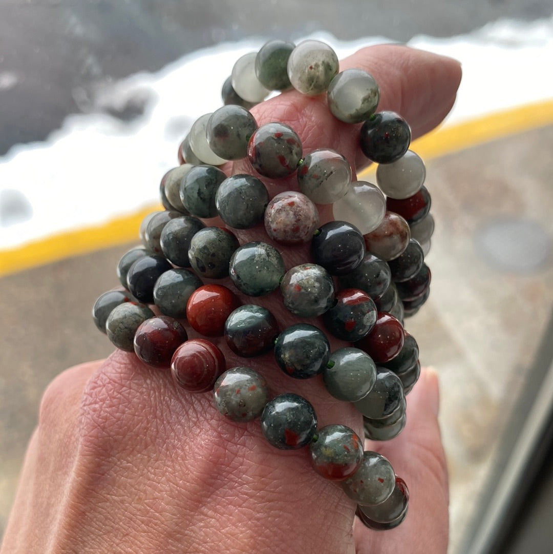 A beautifully crafted 8mm Bloodstone bracelet featuring dark green beads with red inclusions, showcasing its polished finish.