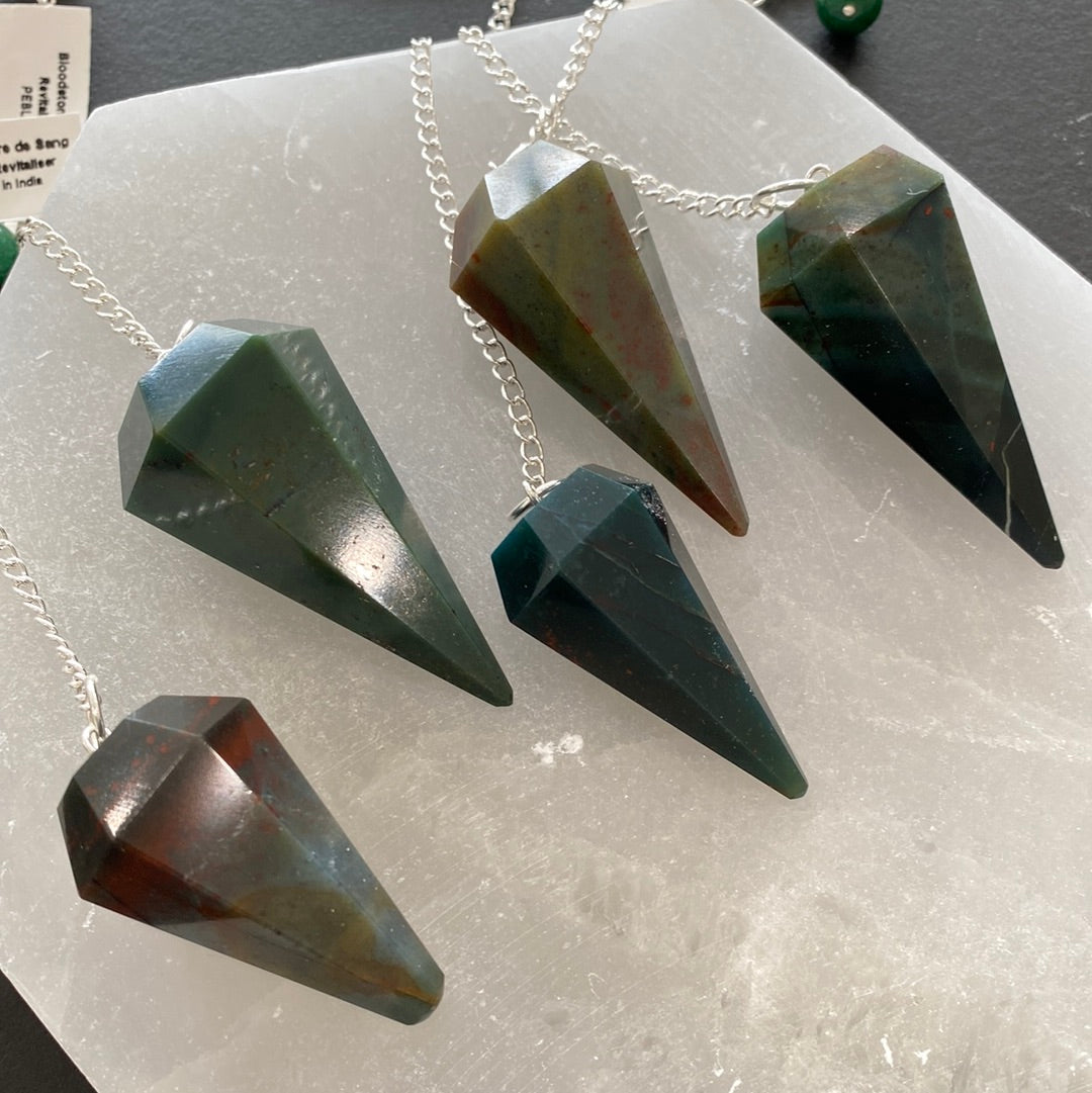 A beautiful bloodstone pendulum on a silver chain, showcasing its unique green and red patterns, perfect for dowsing and energy work.