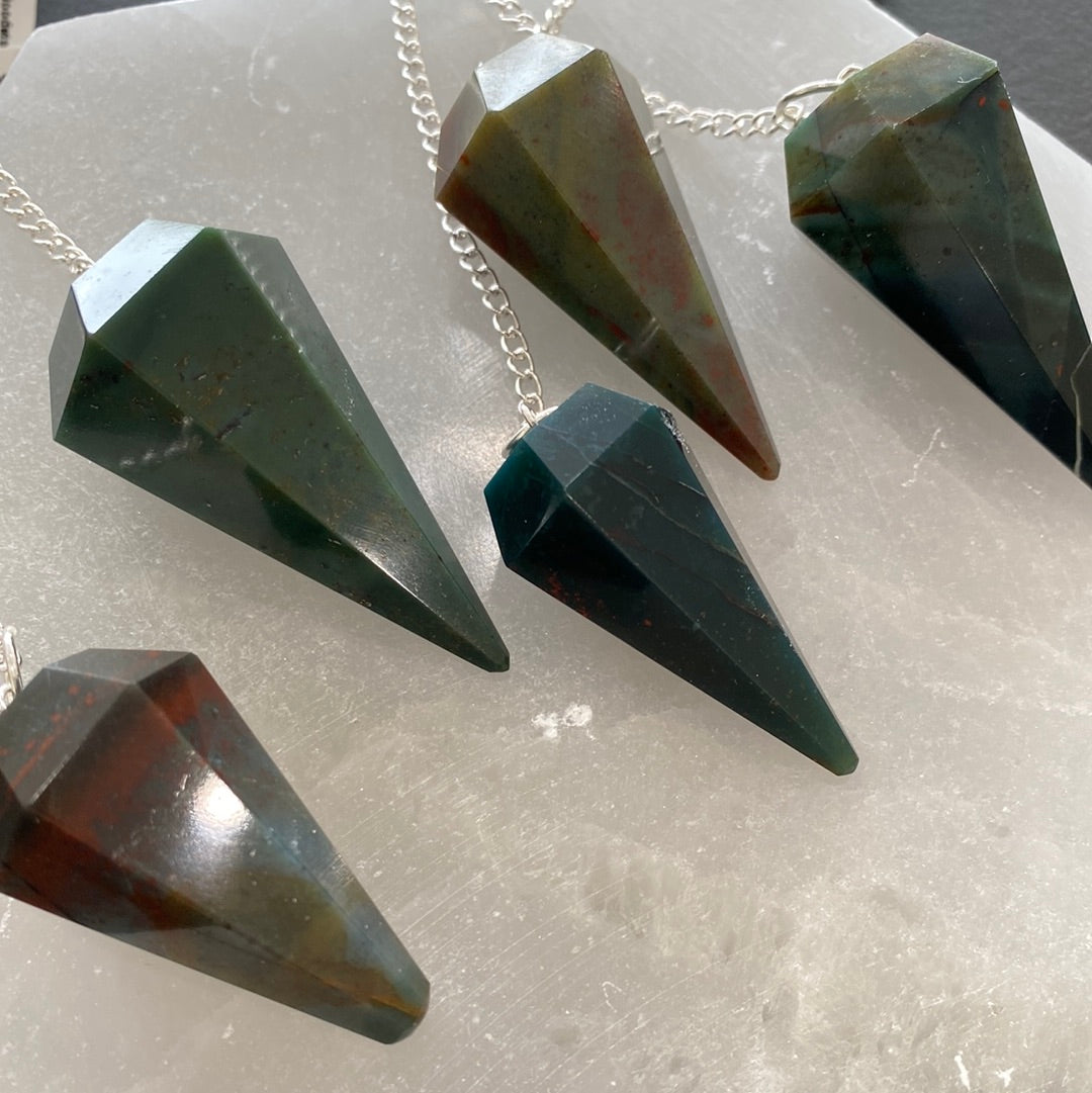 A beautiful bloodstone pendulum on a silver chain, showcasing its unique green and red patterns, perfect for dowsing and energy work.