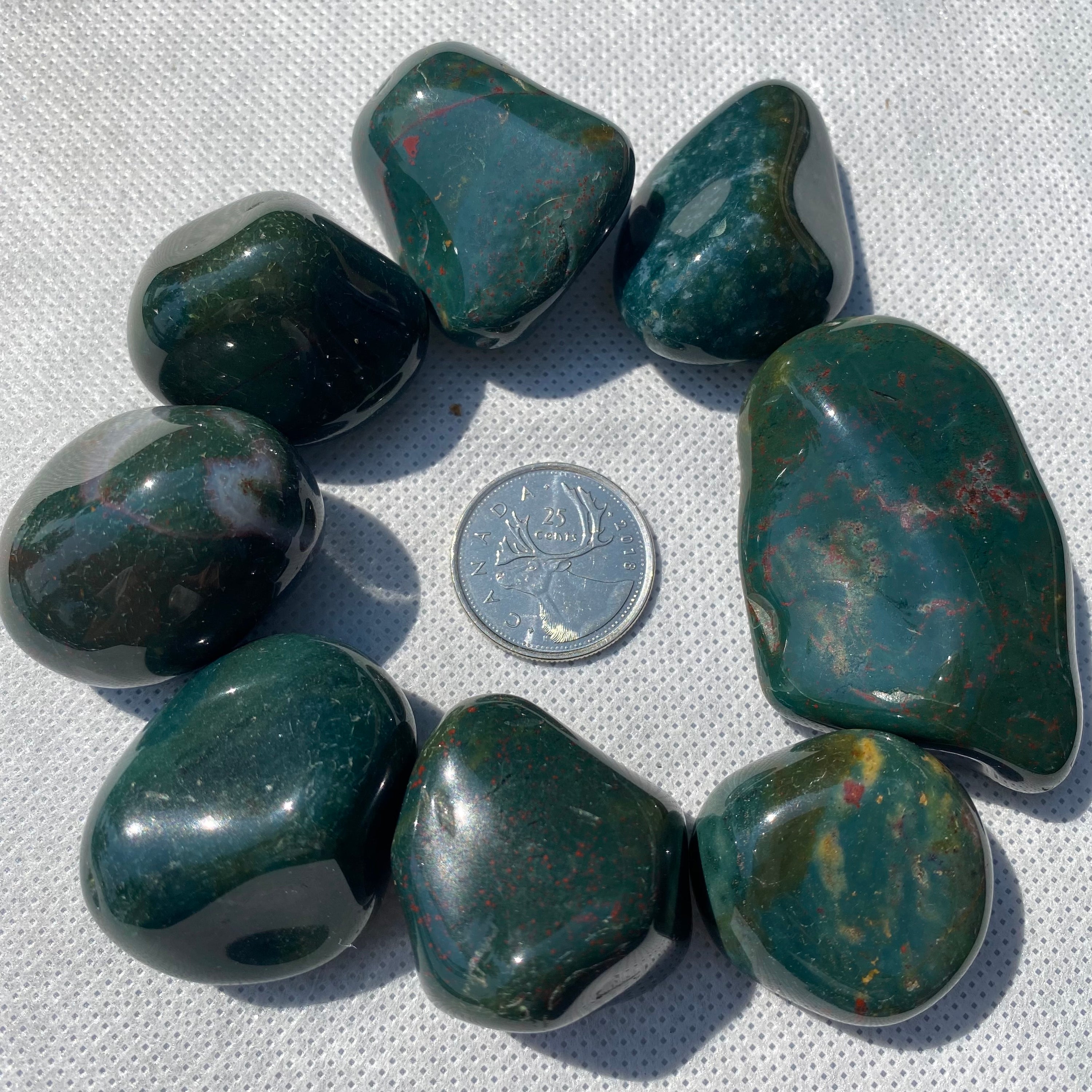 A collection of Bloodstone Tumbled Stones showcasing their unique green and red patterns, perfect for healing and meditation.