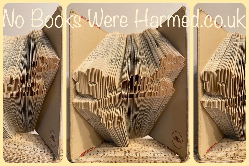 A beautifully crafted hand-folded book art piece made from vintage books, showcasing intricate designs and unique colors.