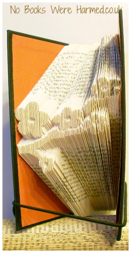 A beautifully crafted hand-folded book art piece made from vintage books, showcasing intricate designs and unique colors.