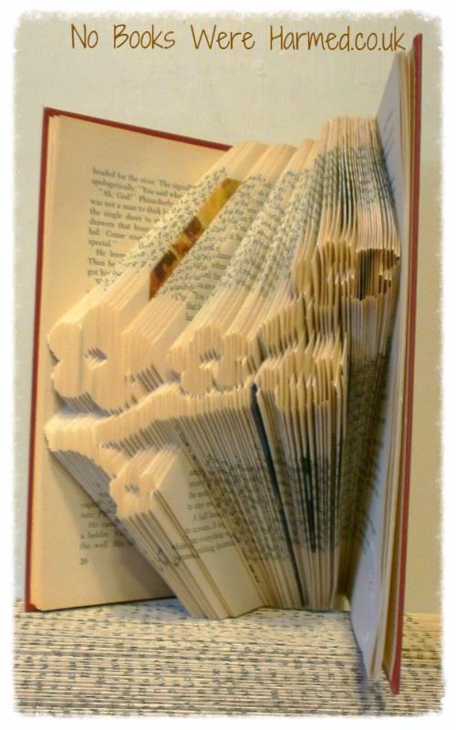 A beautifully crafted hand-folded book art piece made from vintage books, showcasing intricate designs and unique colors.