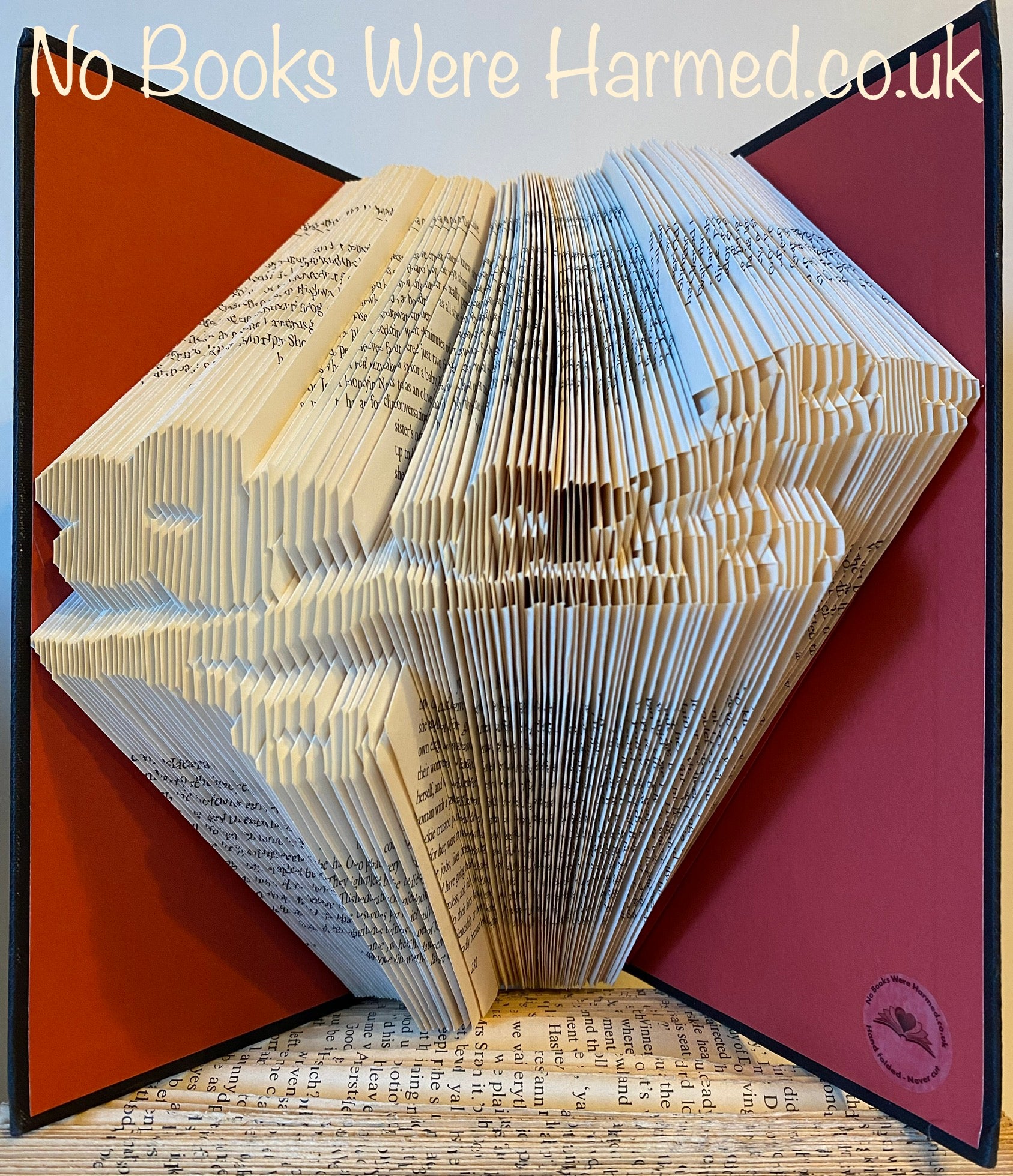 A beautifully crafted hand-folded book art piece made from vintage books, showcasing intricate designs and unique colors.