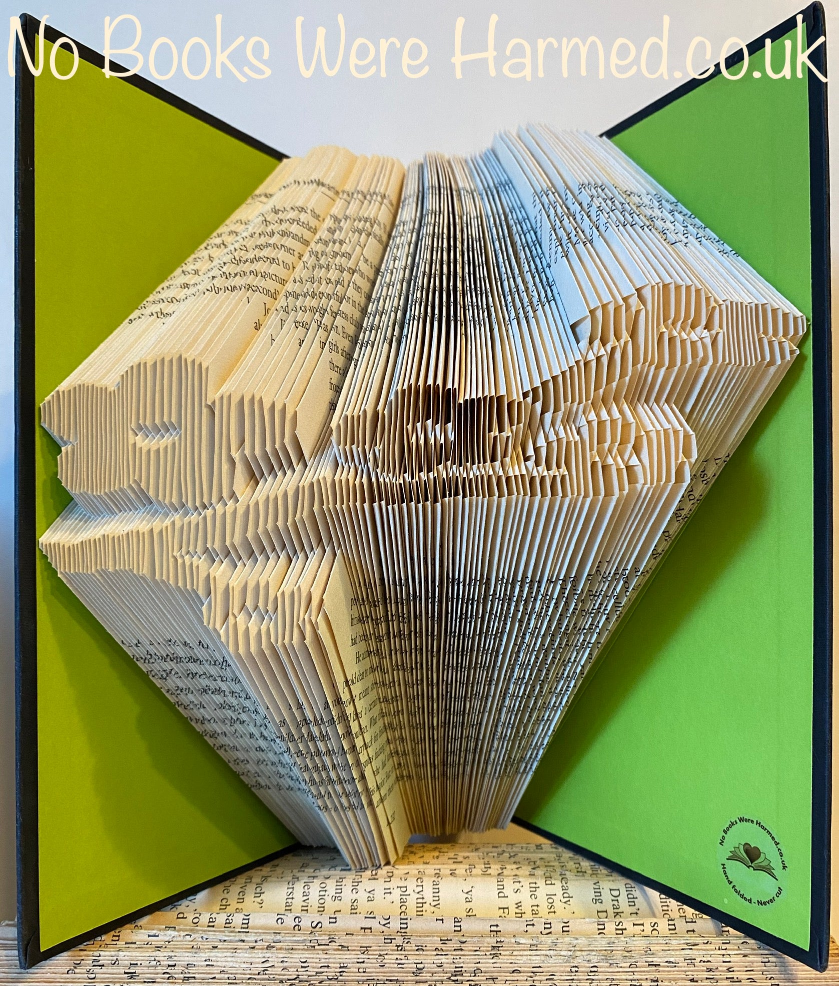 A beautifully crafted hand-folded book art piece made from vintage books, showcasing intricate designs and unique colors.