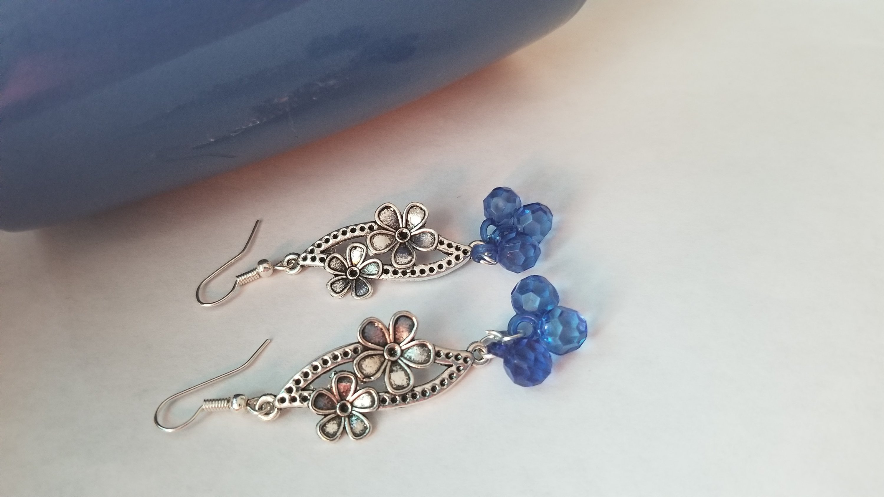 A pair of elegant blue earrings with a translucent finish, showcasing their unique design and shimmering quality.