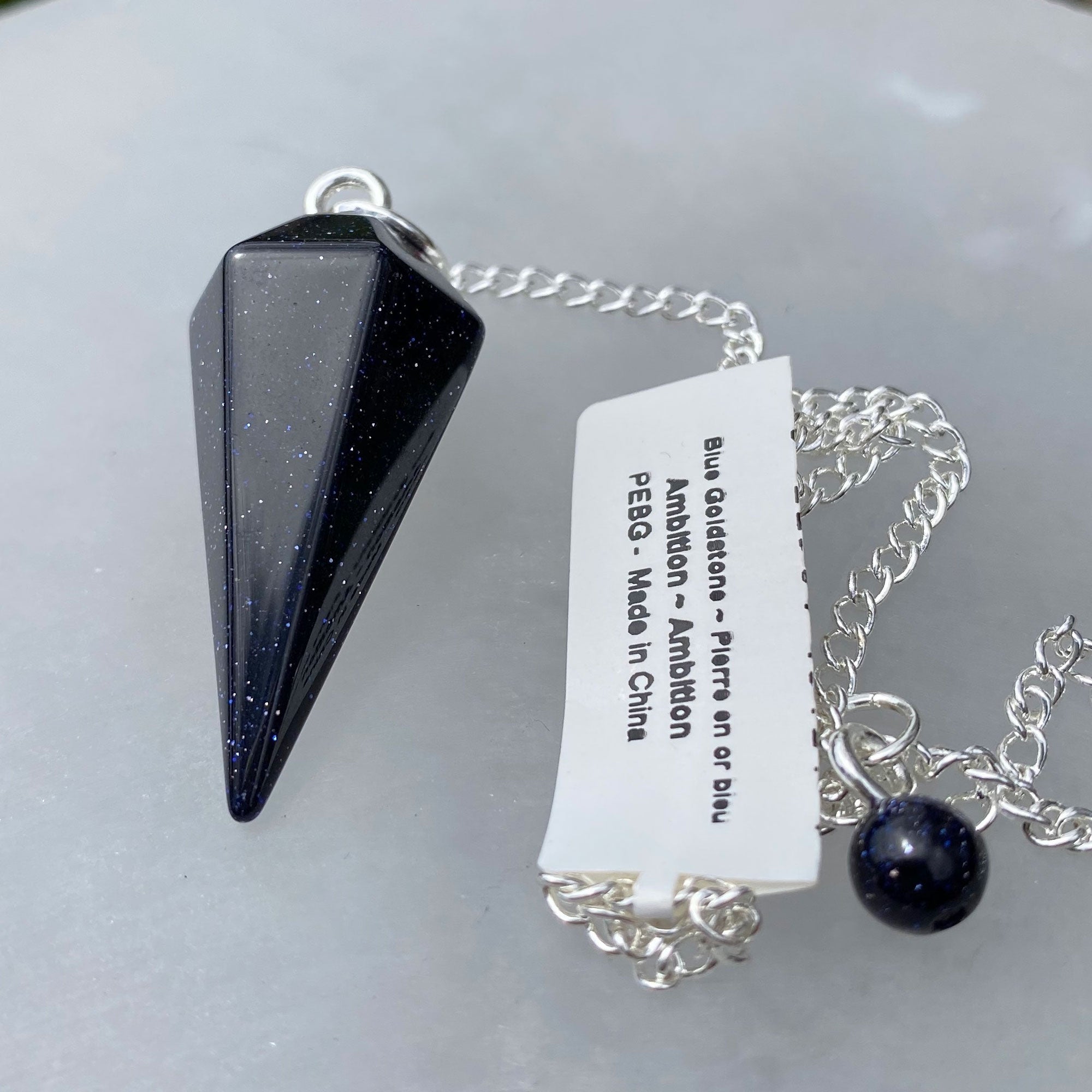 A beautiful Blue Goldstone Pendulum on a silver chain, showcasing its shimmering blue surface and unique gemstone properties.