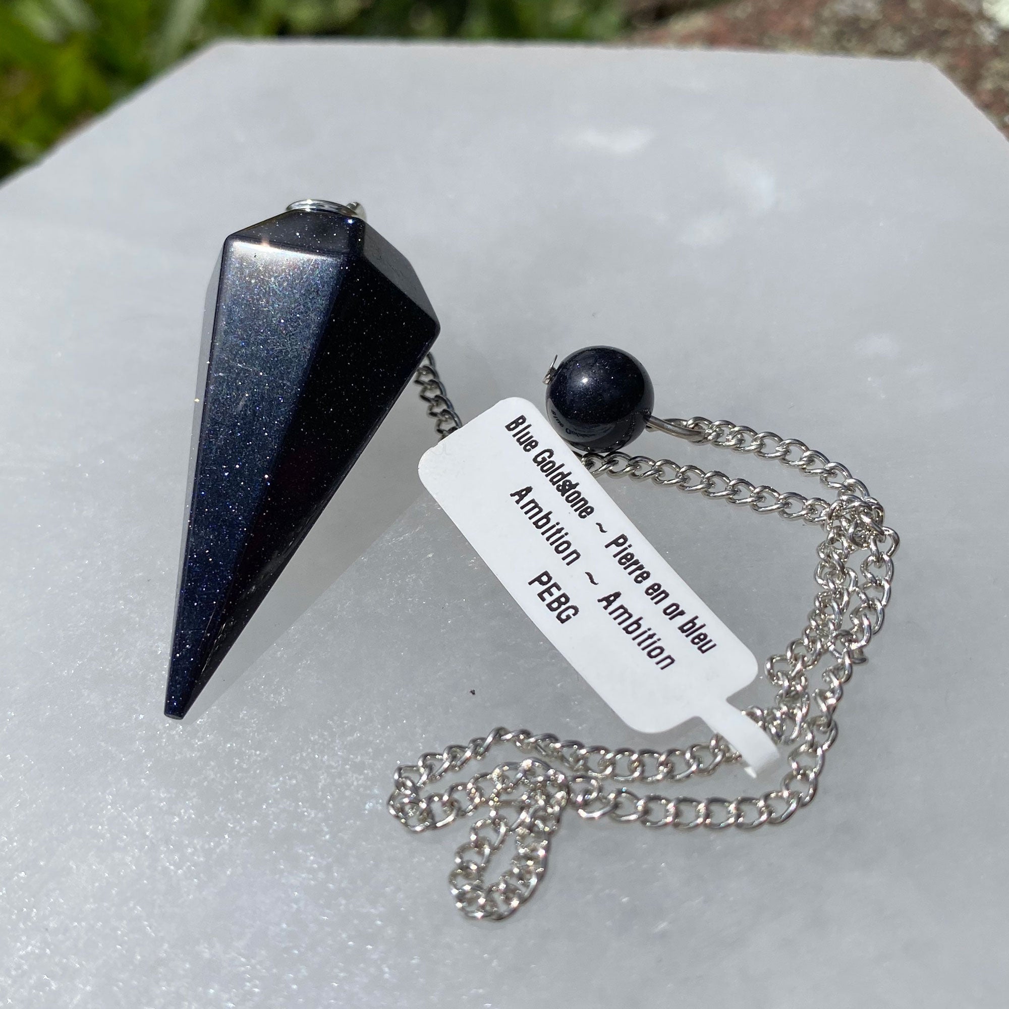 A Blue Goldstone Pendulum on a silver chain, showcasing its shimmering blue and gold flecks, perfect for spiritual guidance and energy work.