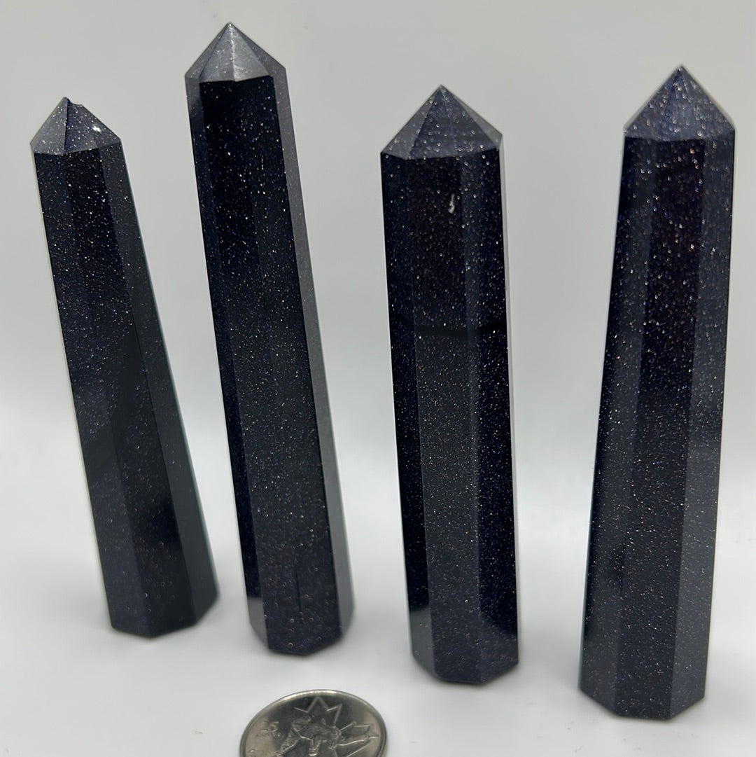 A polished Blue Goldstone point, showcasing its unique shimmering surface and natural gemstone characteristics.