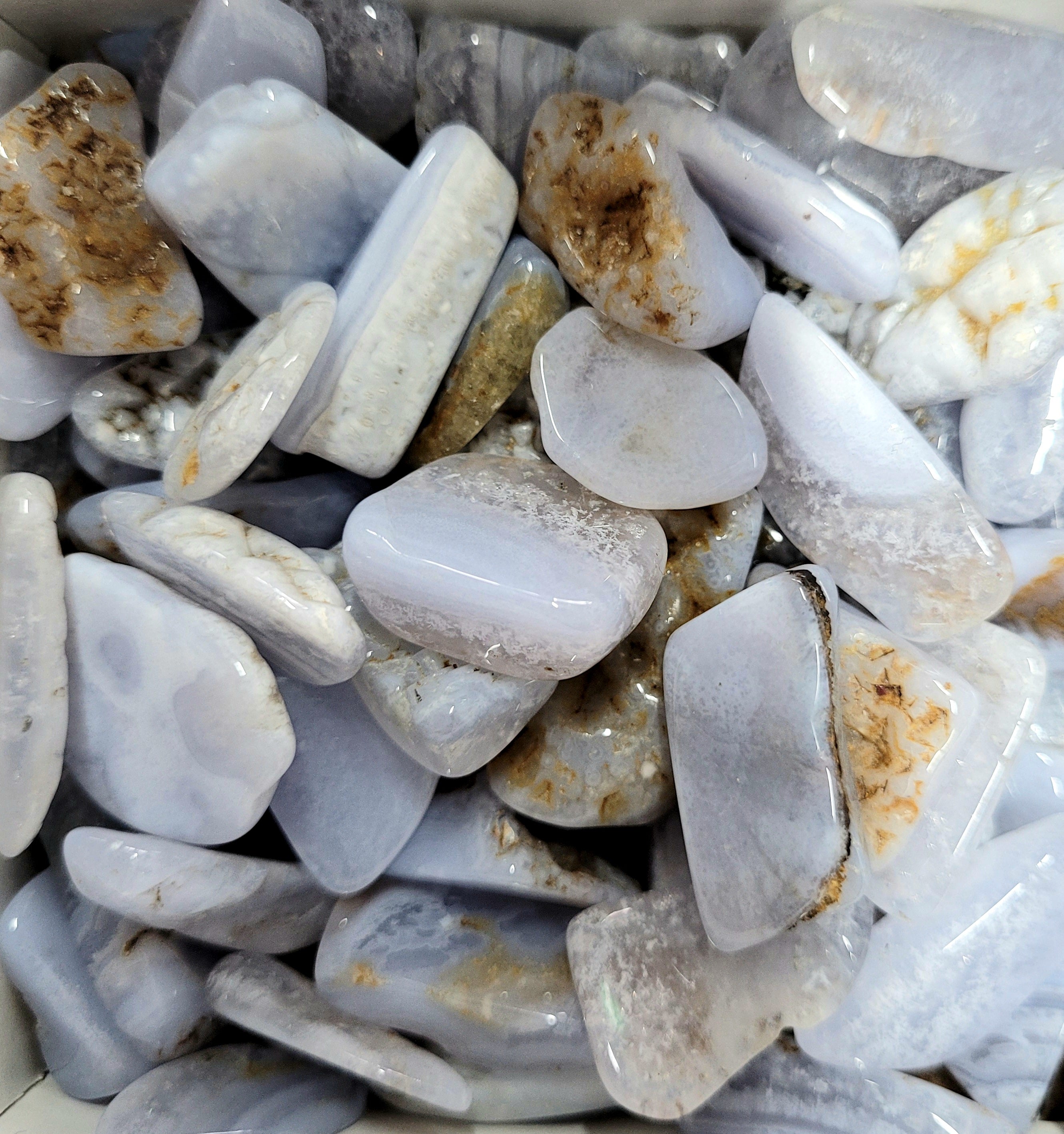 A collection of Blue Lace Agate Tumbled Stones showcasing their light blue color and unique lace-like patterns.