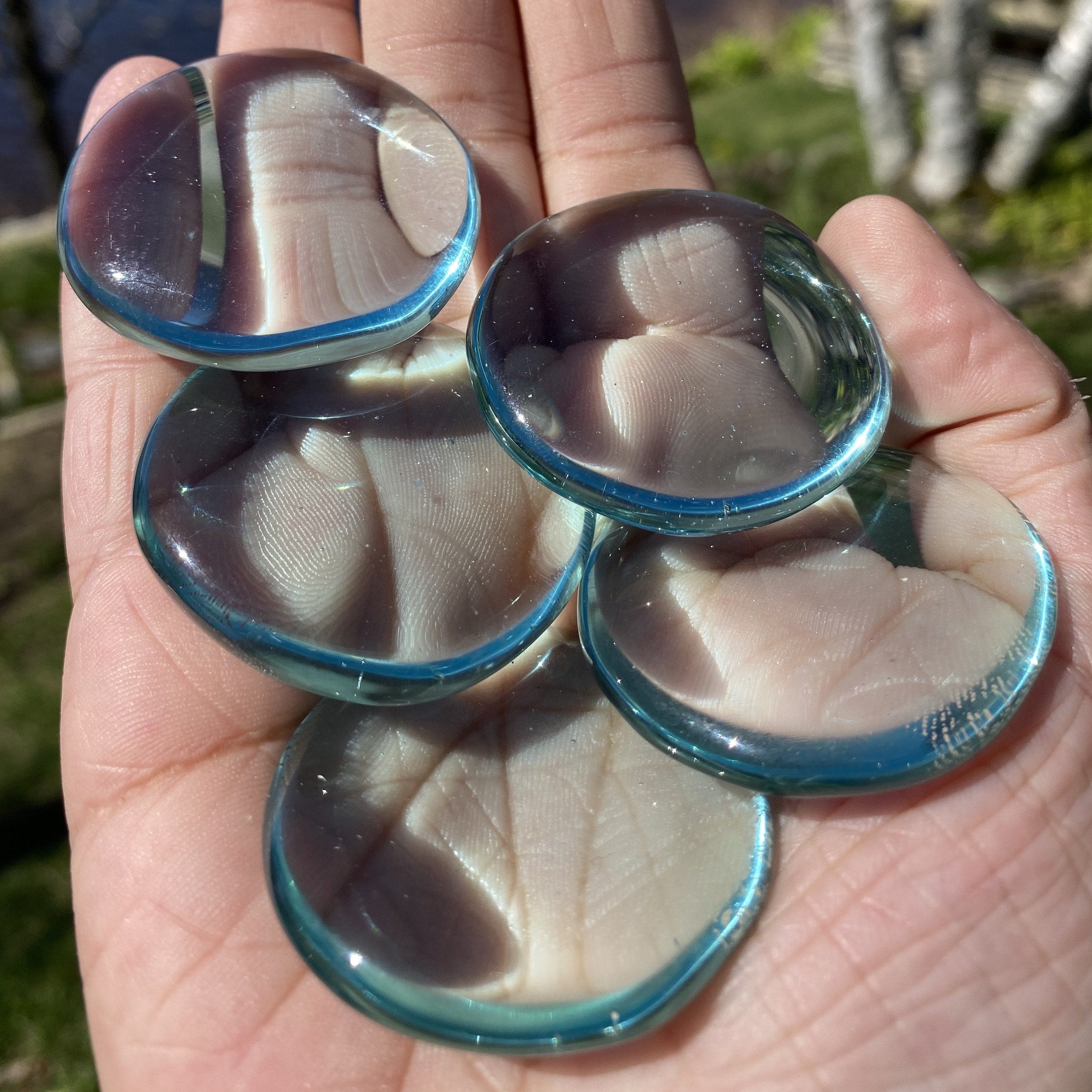 A collection of smooth, polished Blue Obsidian Palm Stones showcasing their vibrant blue color and glossy finish.