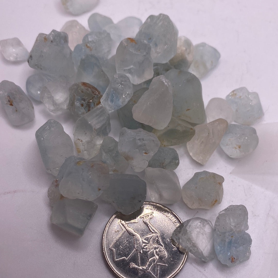 A 100g bag of hand-cut and polished Blue Topaz rough stones, showcasing their vibrant blue color and natural beauty.