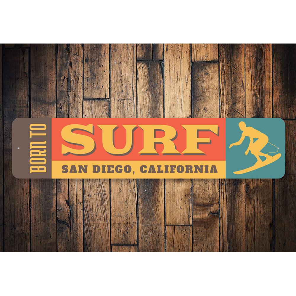 A decorative 'Born to Surf' sign made of durable aluminum, featuring vibrant colors and a beach-themed design, perfect for surf enthusiasts.