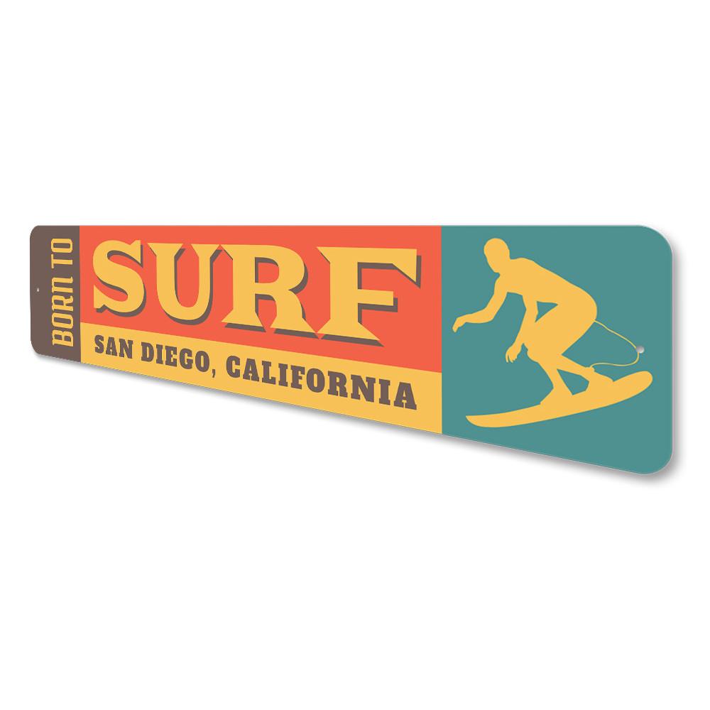 A decorative 'Born to Surf' sign made of durable aluminum, featuring vibrant colors and a beach-themed design, perfect for surf enthusiasts.