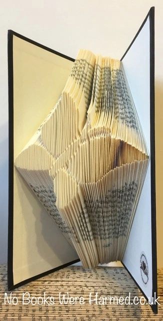 A beautifully hand-folded butterfly art piece made from vintage book pages, showcasing intricate details and unique colors.