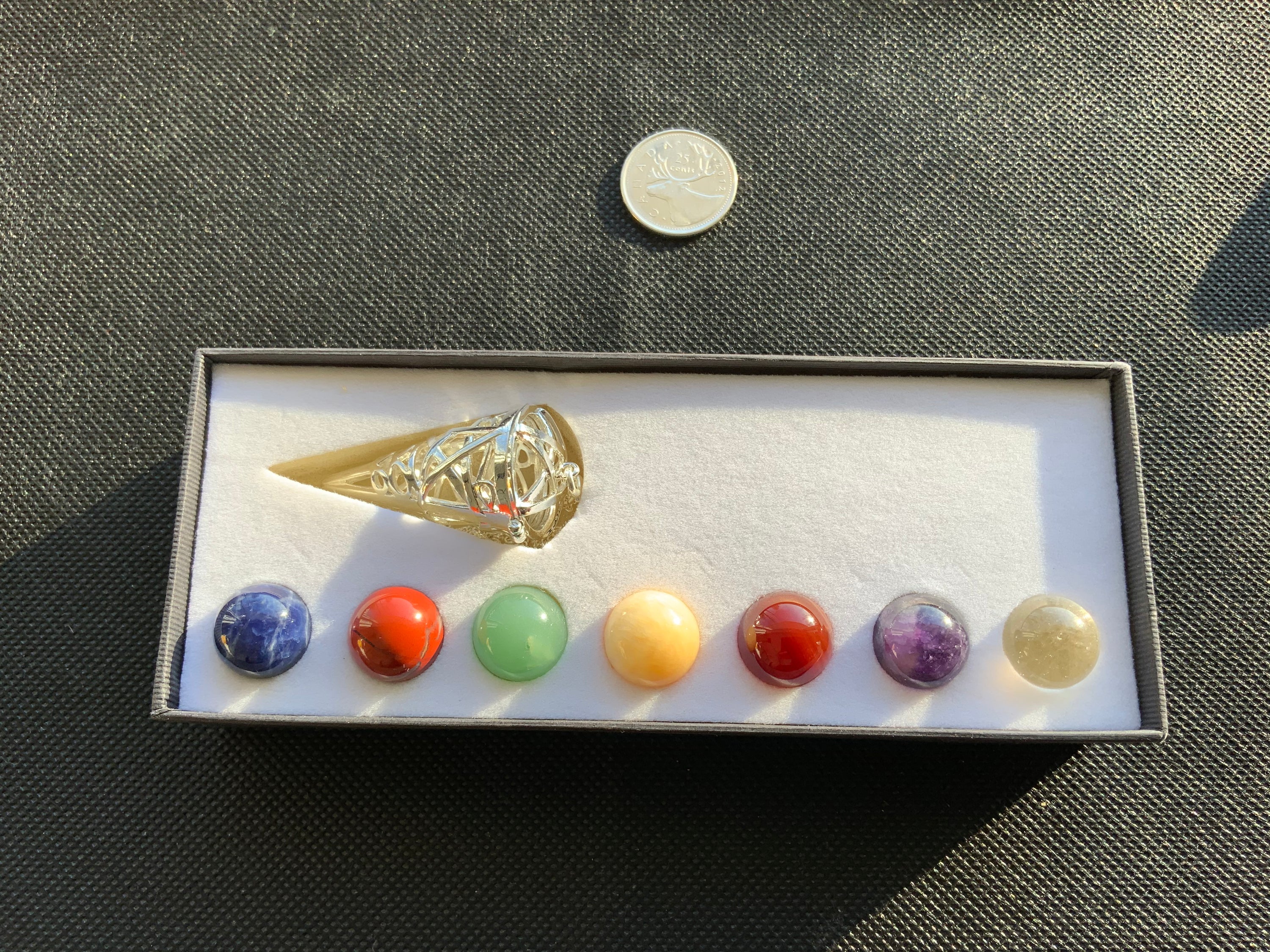 Cage Cone Chakra Pendulum with seven colorful gemstone spheres, beautifully designed for spiritual guidance.