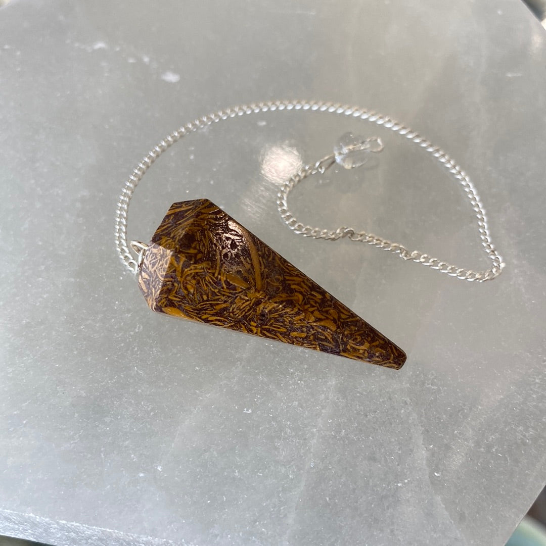 A Calligraphy Stone Pendulum featuring a smooth, brownish-yellow crystal with a cloudy appearance, suspended from a delicate chain.