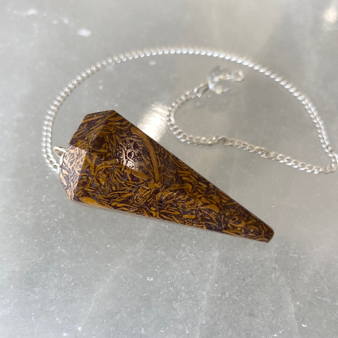 A Calligraphy Stone Pendulum featuring a smooth, brownish-yellow crystal with a cloudy appearance, suspended from a delicate chain.