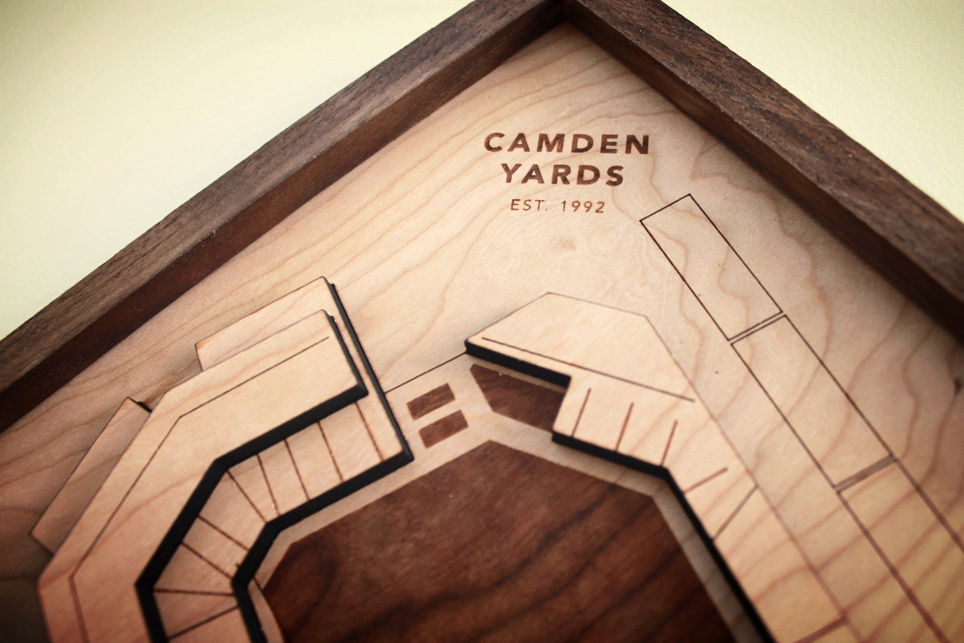 A detailed wooden replica of Camden Yards stadium, showcasing premium hardwood craftsmanship with a black walnut frame.