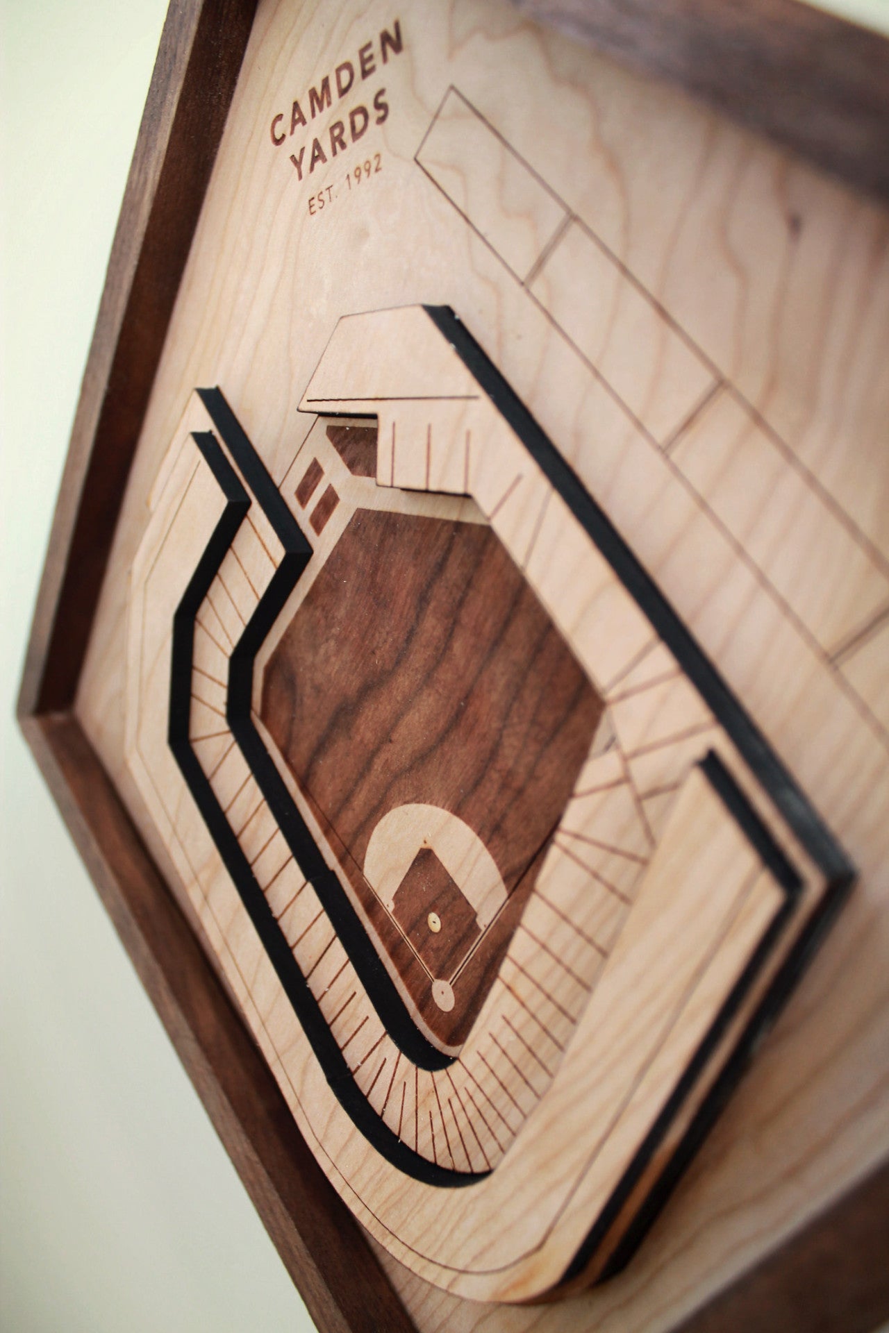 A detailed wooden replica of Camden Yards stadium, showcasing premium hardwood craftsmanship with a black walnut frame.