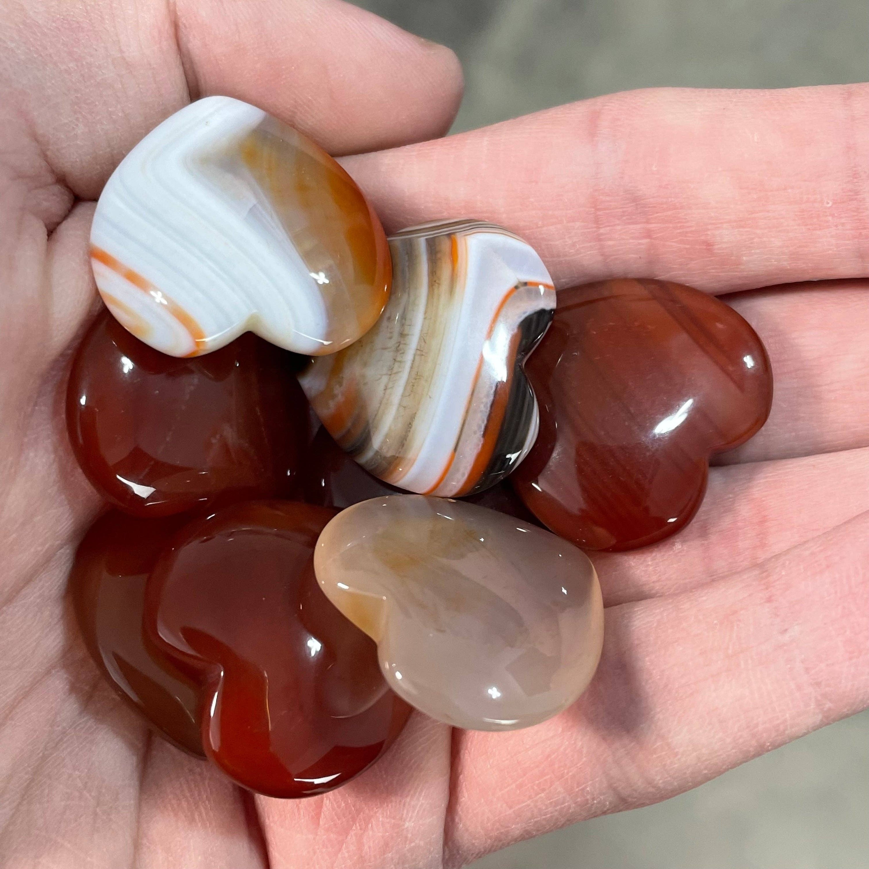 A collection of randomly selected carnelian hearts showcasing vibrant colors and unique patterns, each heart is polished and smooth.