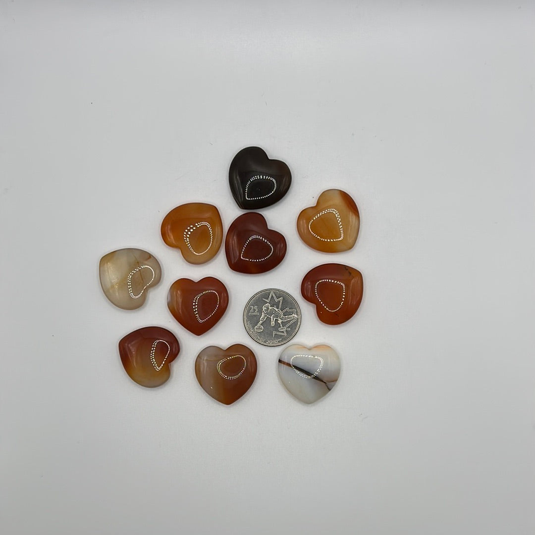 A collection of randomly selected carnelian hearts showcasing vibrant colors and unique patterns, each heart is polished and smooth.