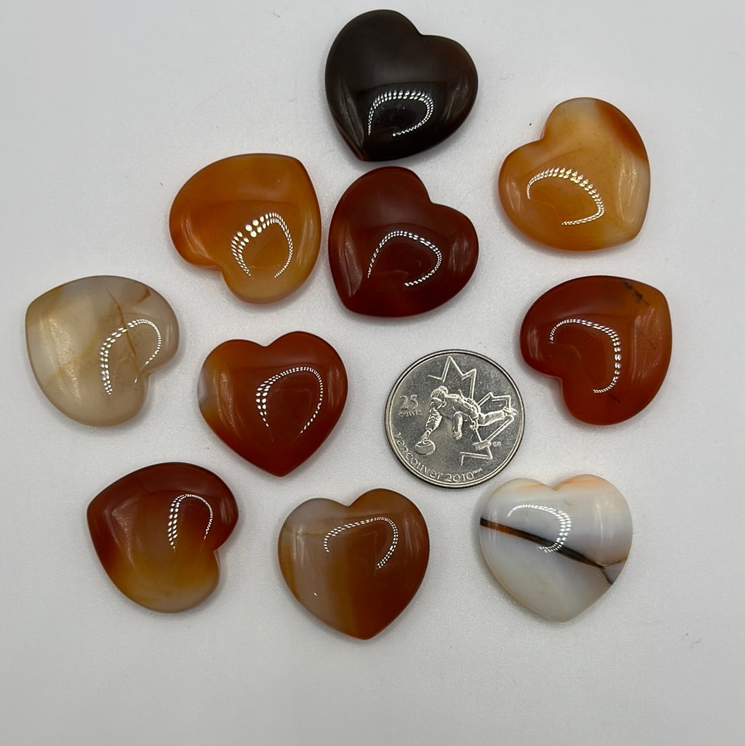 A collection of randomly selected carnelian hearts showcasing vibrant colors and unique patterns, each heart is polished and smooth.