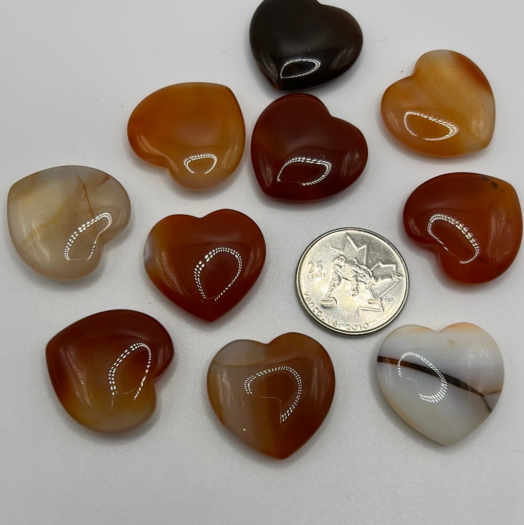 A collection of randomly selected carnelian hearts showcasing vibrant colors and unique patterns, each heart is polished and smooth.