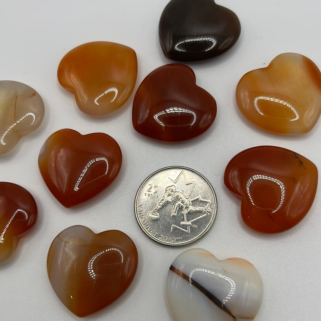 A collection of randomly selected carnelian hearts showcasing vibrant colors and unique patterns, each heart is polished and smooth.