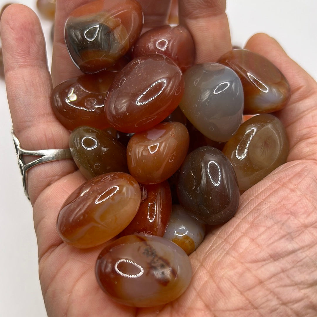 High-quality tumbled Carnelian stone showcasing vibrant red and orange colors, symbolizing motivation and self-esteem.