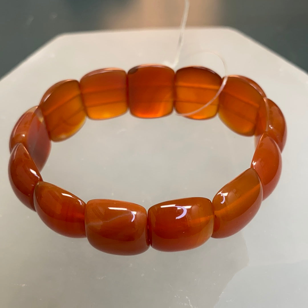 A stylish Carnelian Oval Beaded Bracelet featuring vibrant red and orange semi-precious stones, perfect for enhancing motivation and self-esteem.