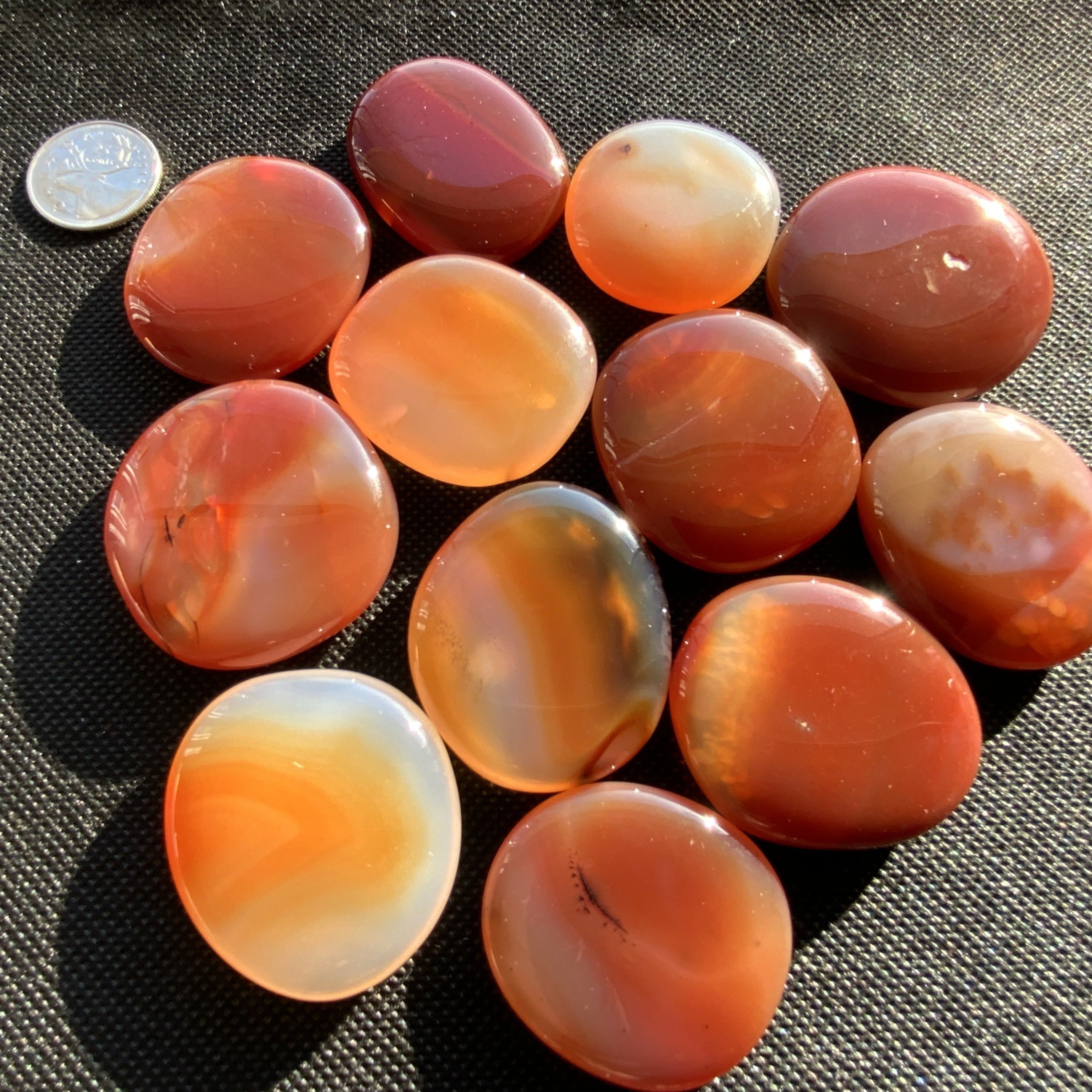 A collection of polished Carnelian palm stones showcasing their vibrant red and orange hues, perfect for meditation and creativity.