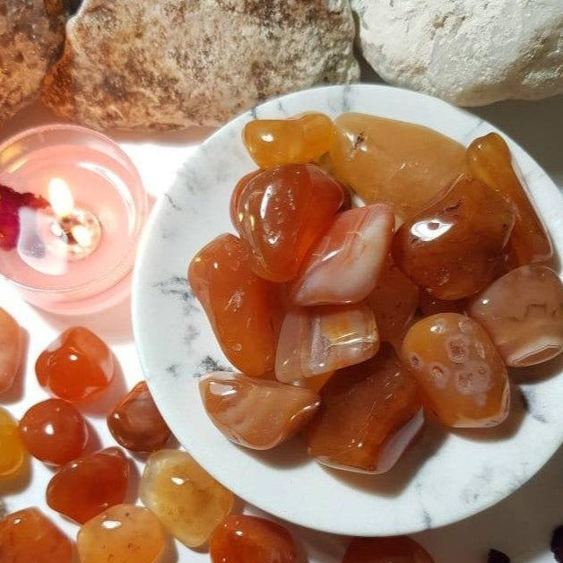 A collection of smooth, polished Carnelian Tumbled Stones showcasing their warm orange and reddish hues, ideal for grounding and motivation.