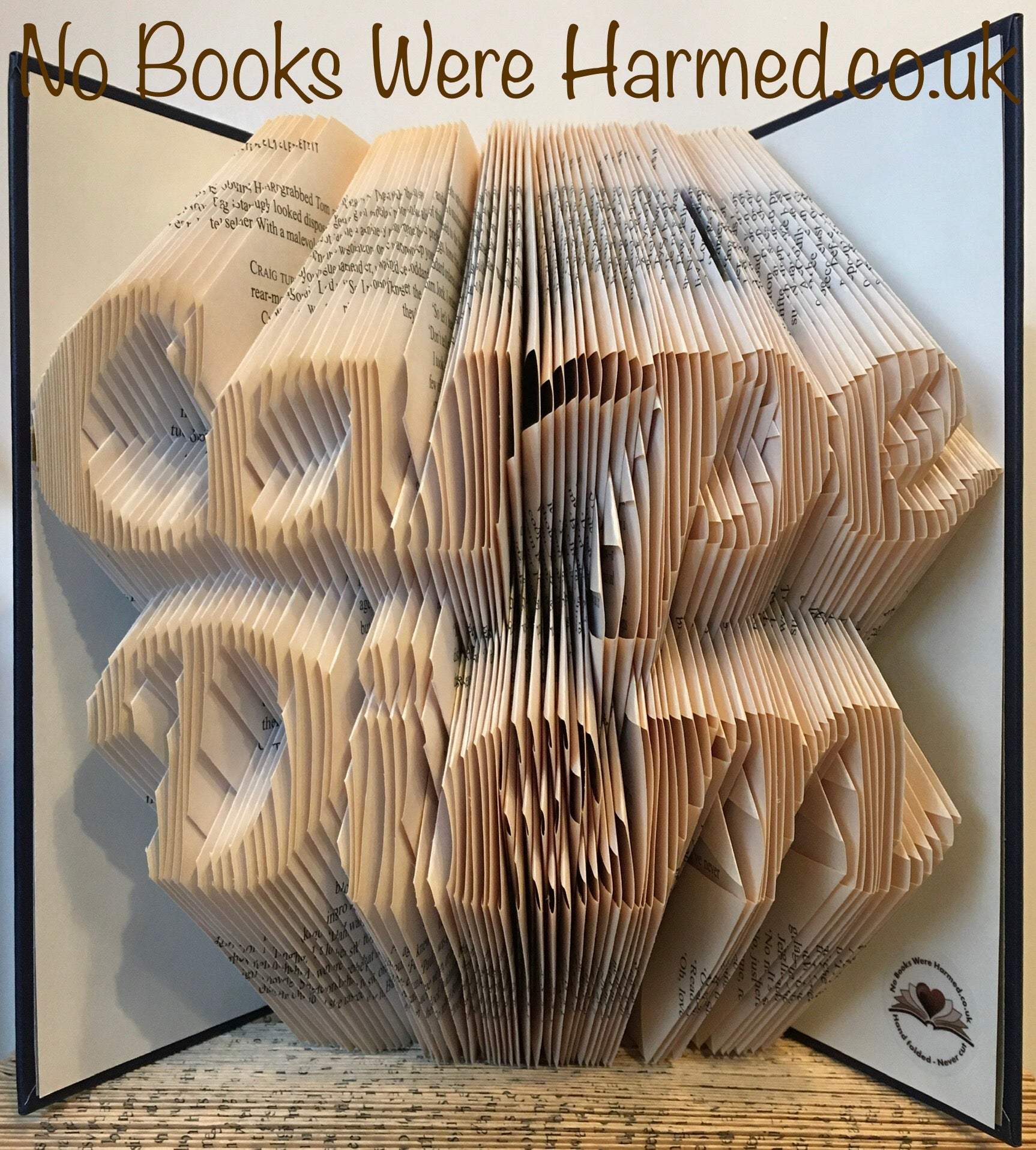 Handcrafted book art titled Carpe Diem, featuring intricately folded pages from vintage books, showcasing unique colors and designs.