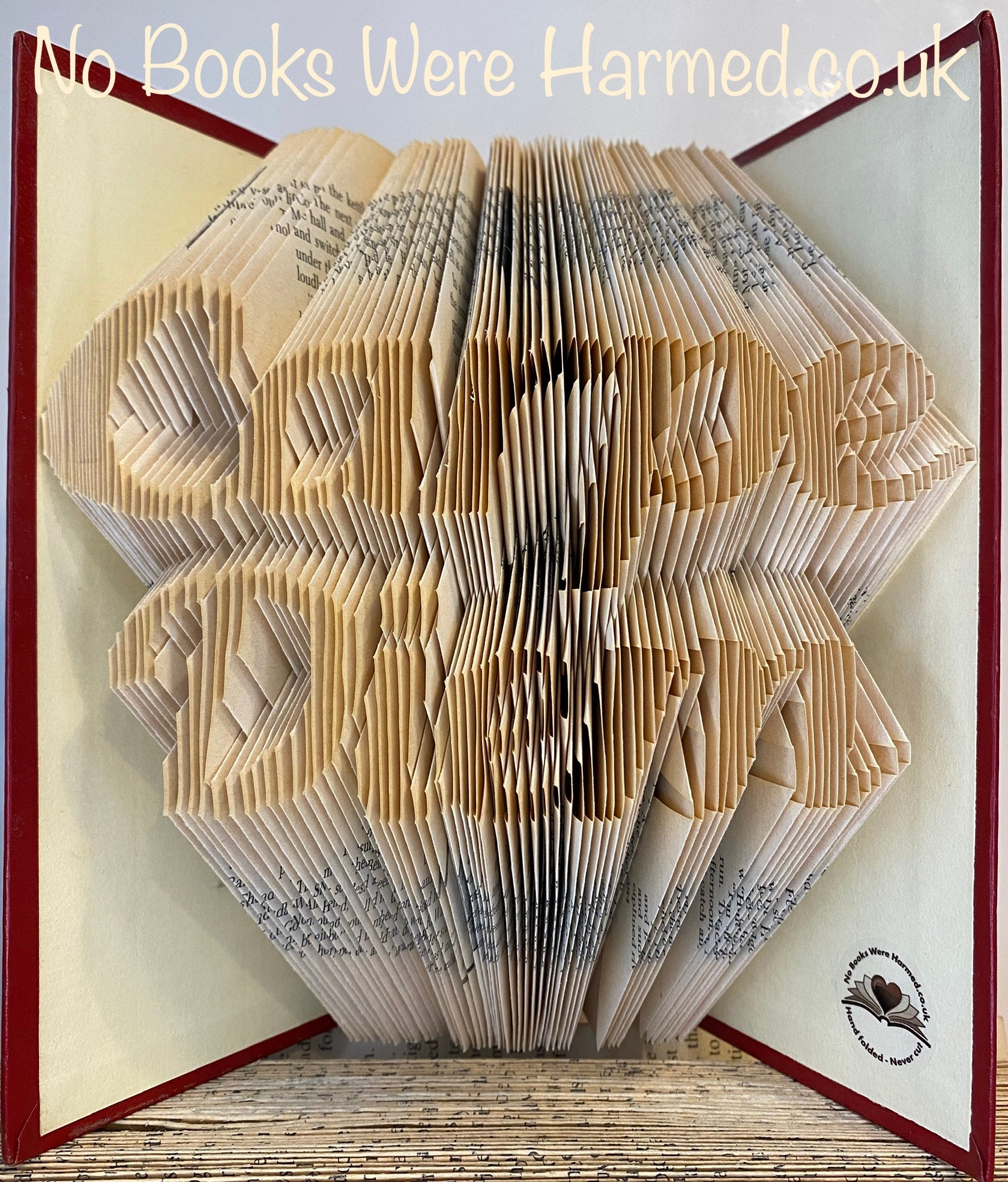 Handcrafted book art titled Carpe Diem, featuring intricately folded pages from vintage books, showcasing unique colors and designs.