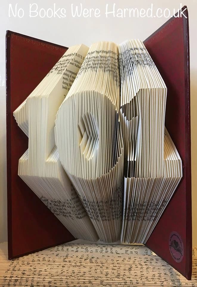 Hand-folded book art featuring customizable triple milestone numbers from vintage books.