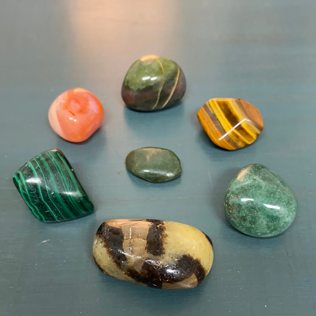 Change Maker Tumbled Stone Bundle featuring seven unique healing stones in a velvet gemstone bag, showcasing their natural beauty and variety.