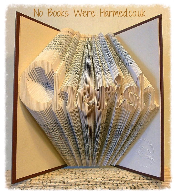 A unique hand-folded book art piece made from reclaimed vintage books, showcasing intricate designs and varying colors.