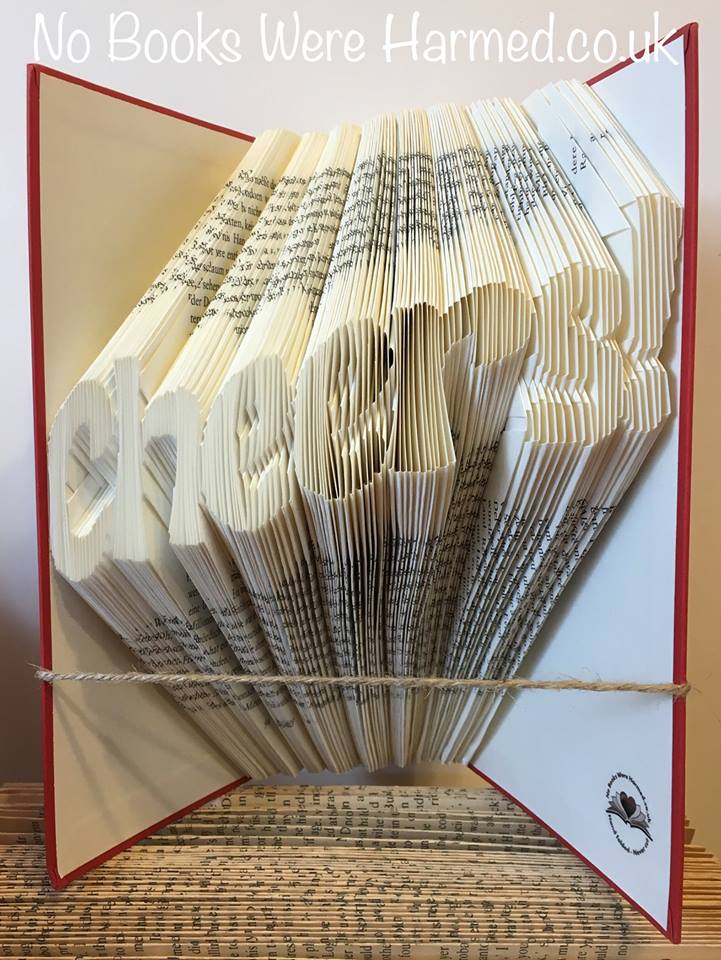 A beautifully crafted piece of hand-folded book art made from vintage books, showcasing intricate designs and unique colors.