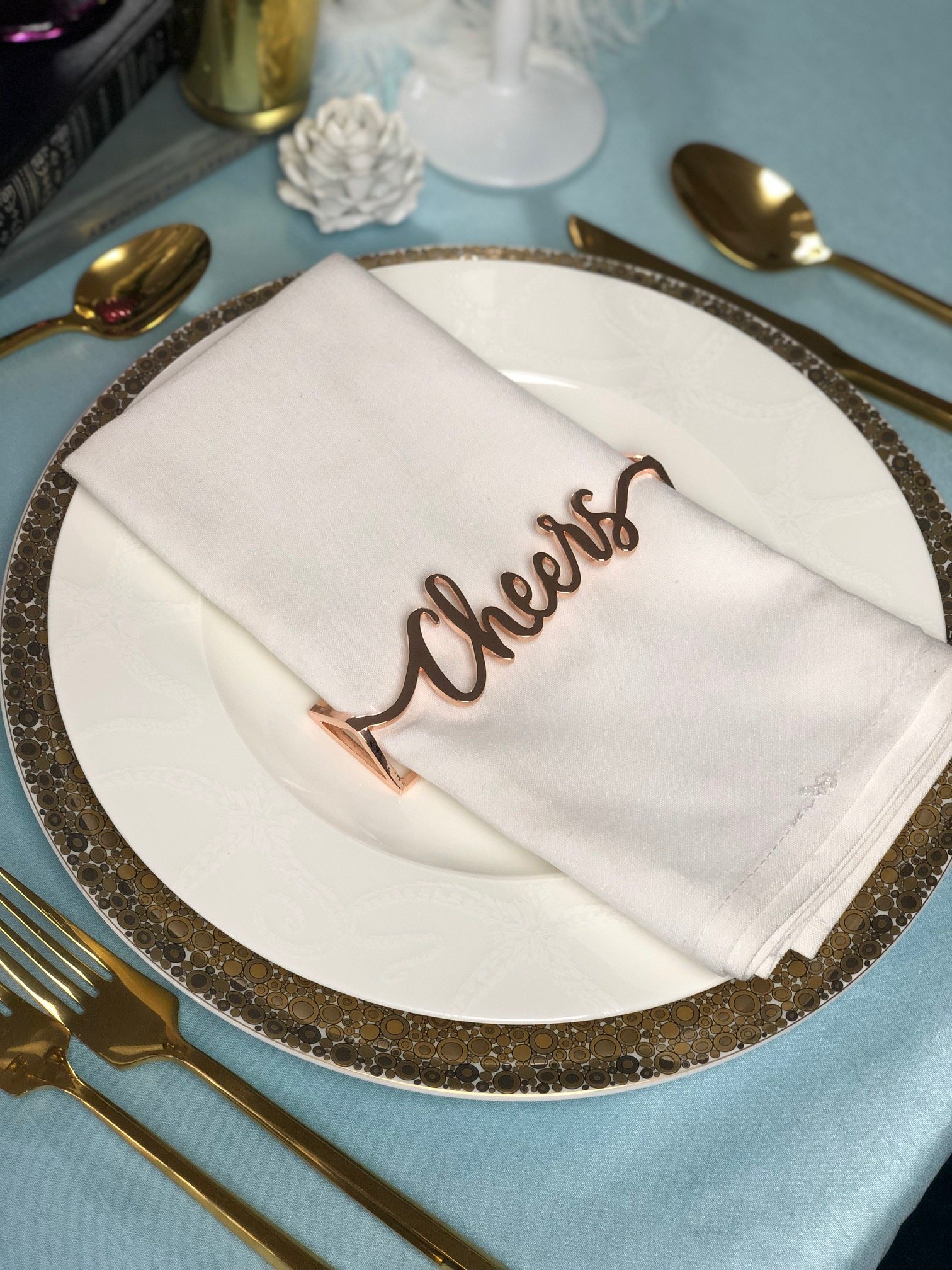 Set of 4 rose gold Cheers napkin wraps elegantly displayed on a table.